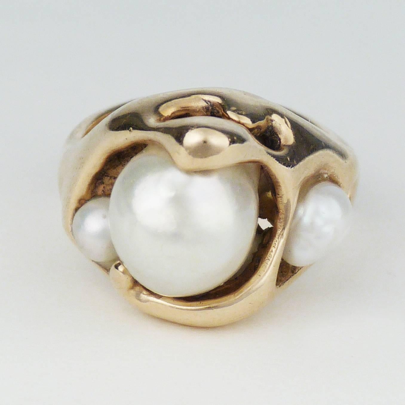 An exquisite piece by Hopi master Charles Loloma, created by using the lost wax technique of casting. The sinuous form mirrors gold in its liquid state. Three pearls. Signature was etched by the artist. Ring size 6.25.