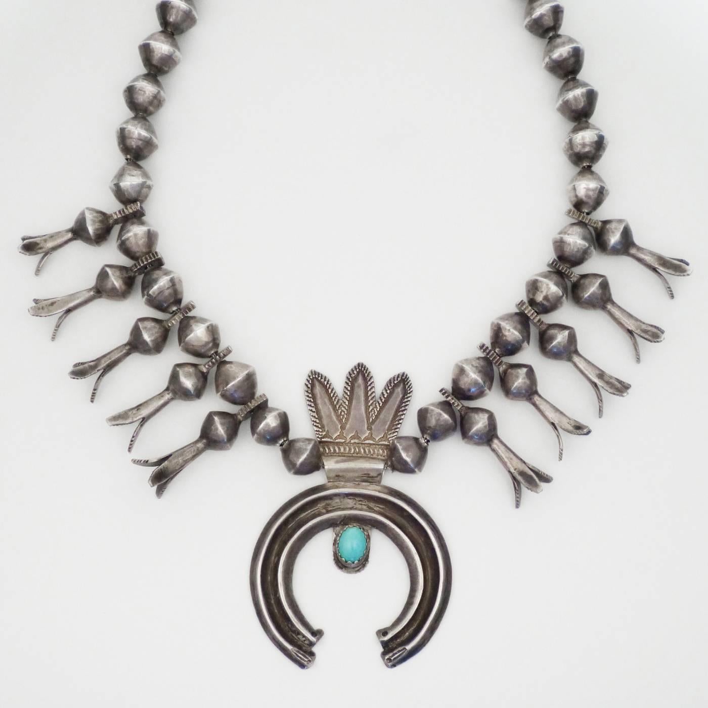 An iconic example of early Navajo silverwork, this naja features stamping and cold chisel decorations on hand-hammered ingot silver with handmade beads and naja. The naja with the headdress/feathered element is incredible rare. 25 1/2