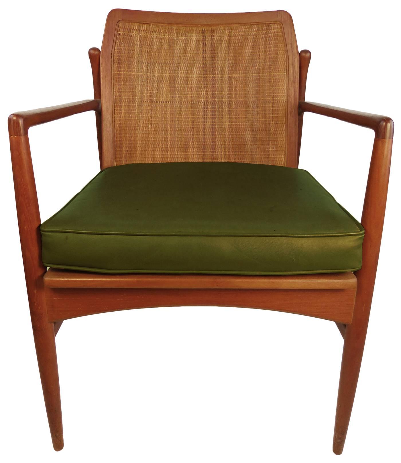 A Classic Mid-Century Modern armchair, with caned backrest and green vinyl cushion.