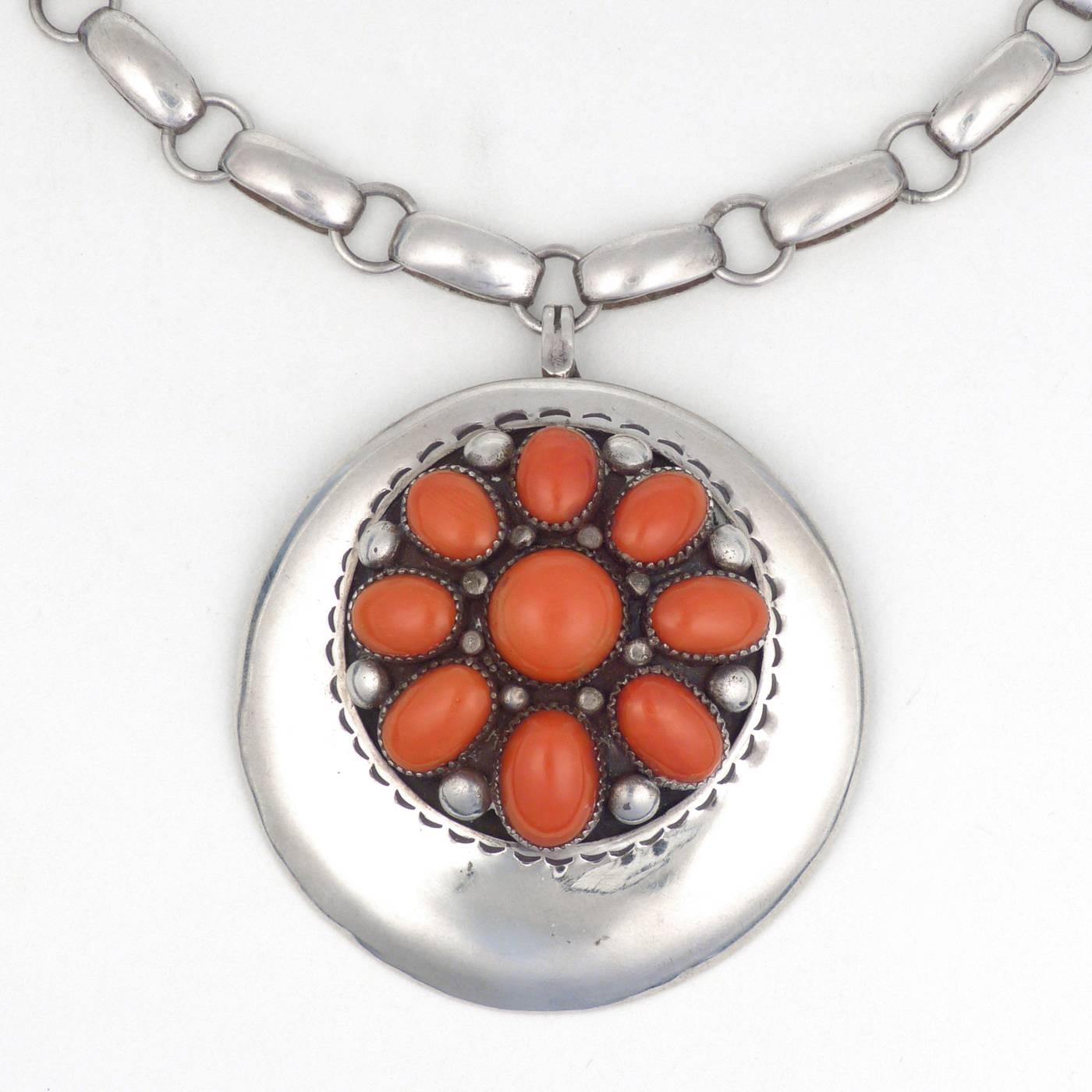 A gorgeous pendant (also able to be worn as a pin) with nine Mediterranean coral cabochons. Suspended from a handmade chain, most likely executed by Julian Lovato during his tenure at the Thunderbird Shop. Chain measures 14