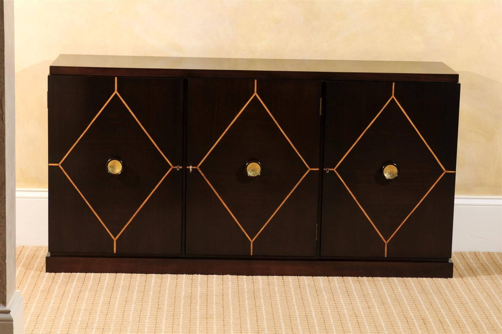 An exceptional cabinet or buffet by Tommi Parzinger for Charak Modern, circa 1950. Expertly crafted Mahogany case construction. The three doors are accented with a diamond pattern inlay in maple and mahogany/brass knobs. Configured with a center