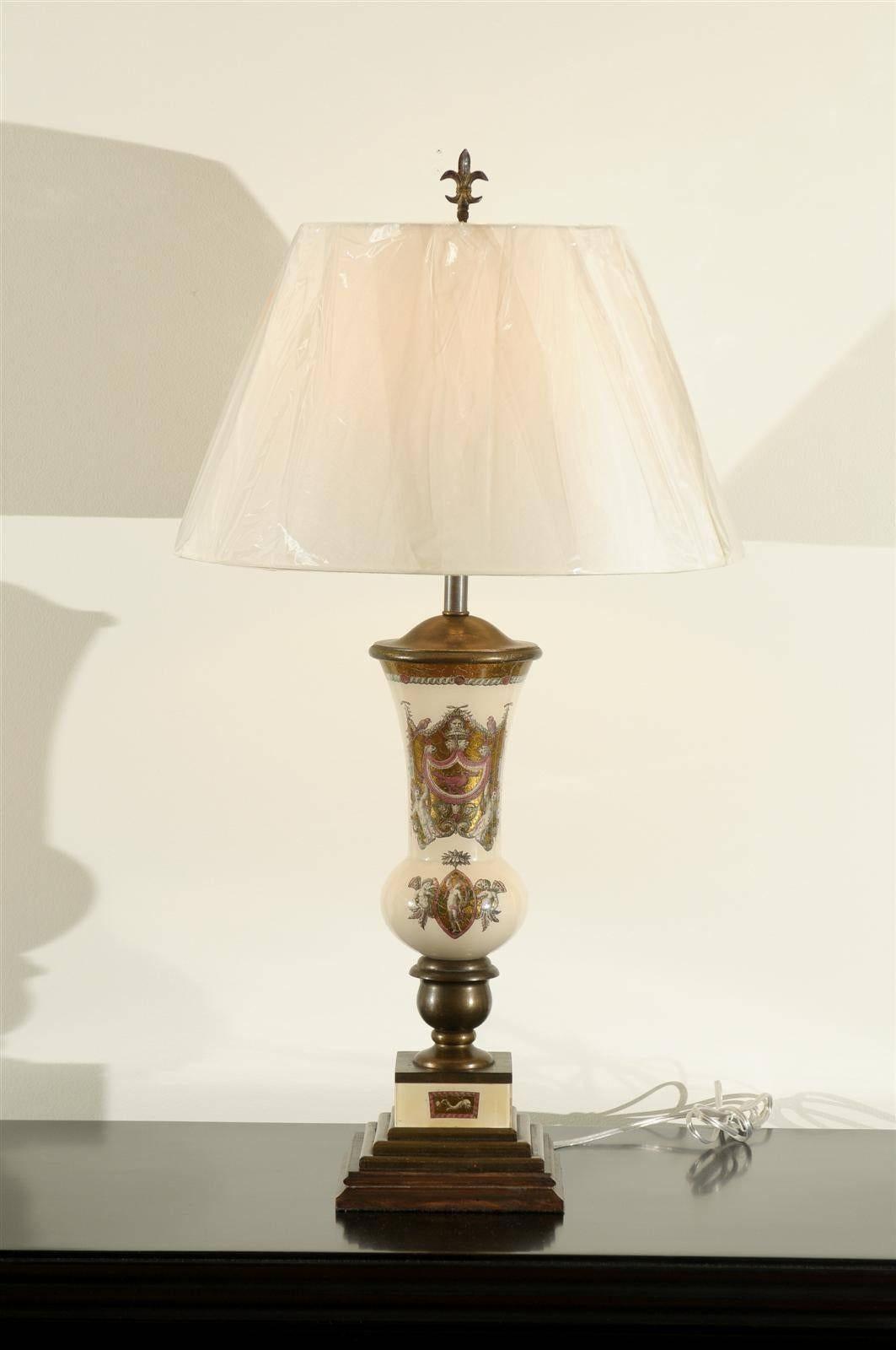 A stunning pair of reverse painted glass lamps. A subtle, whimsical, almost surreal interpretation of the neoclassic style. Cream vessels with motifs executed in charcoal, gold and raspberry. Distressed bronze painted wood base and accents. Each