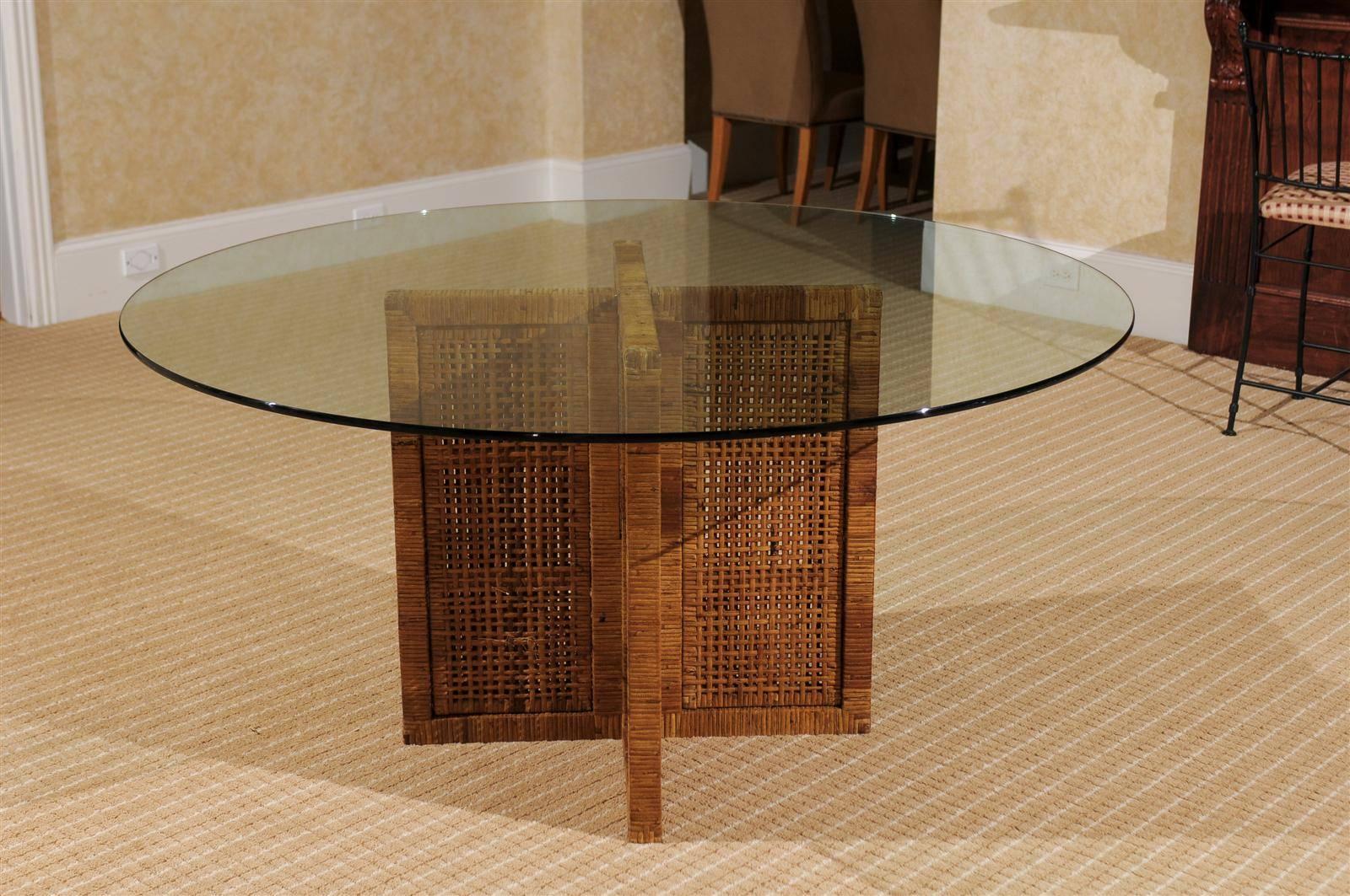 A lovely dining table, circa 1970. Hardwood base wrapped in rattan veneer with cane panel insets; 60