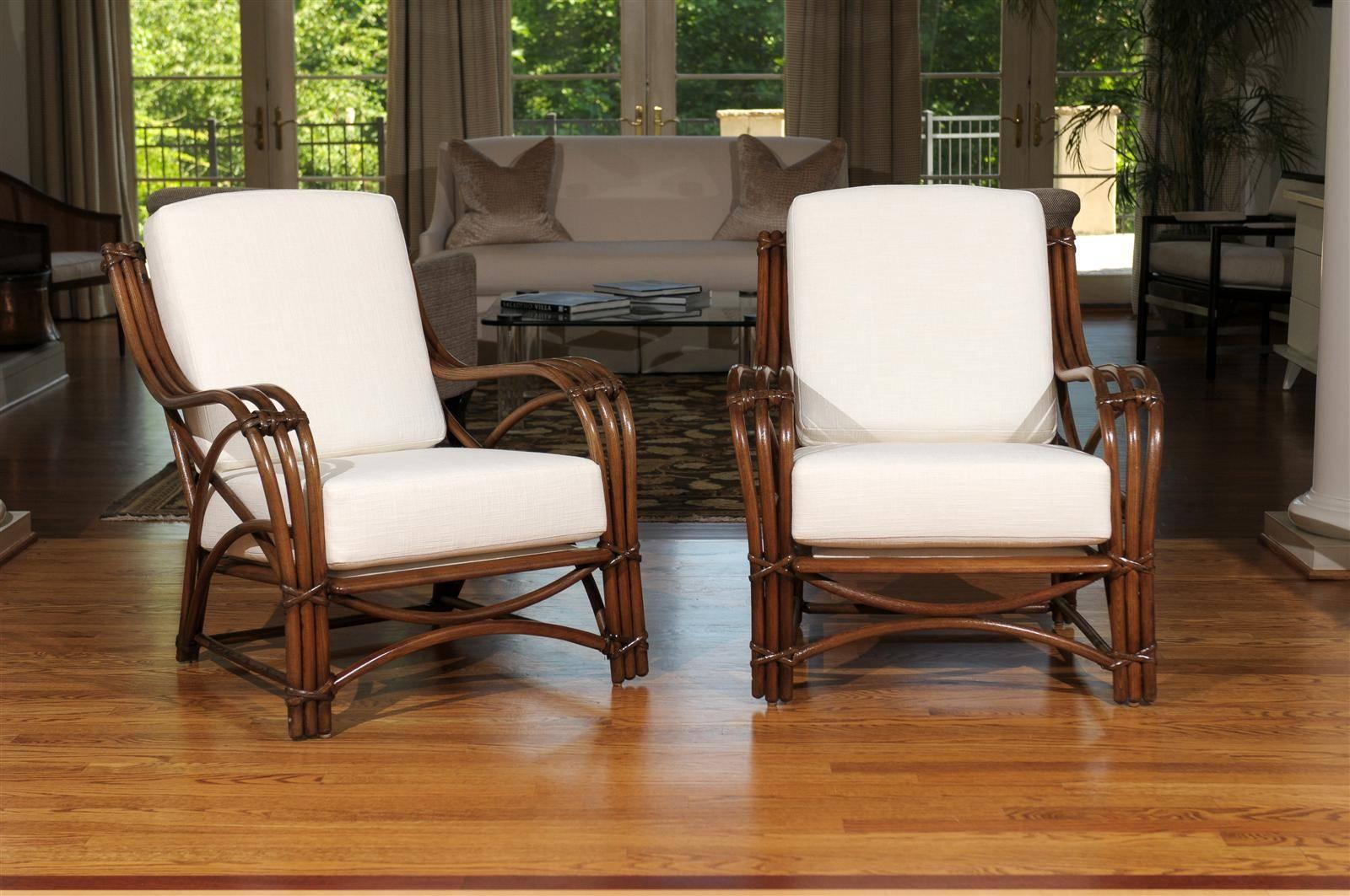 A beautiful pair of lounge or club chairs, circa 1950. Designed to give the appearance of rattan, the chairs are actually made from bent oak. Chair bindings and detail are in rattan. Stout and exceptionally crafted. Matching three-seat sofa also