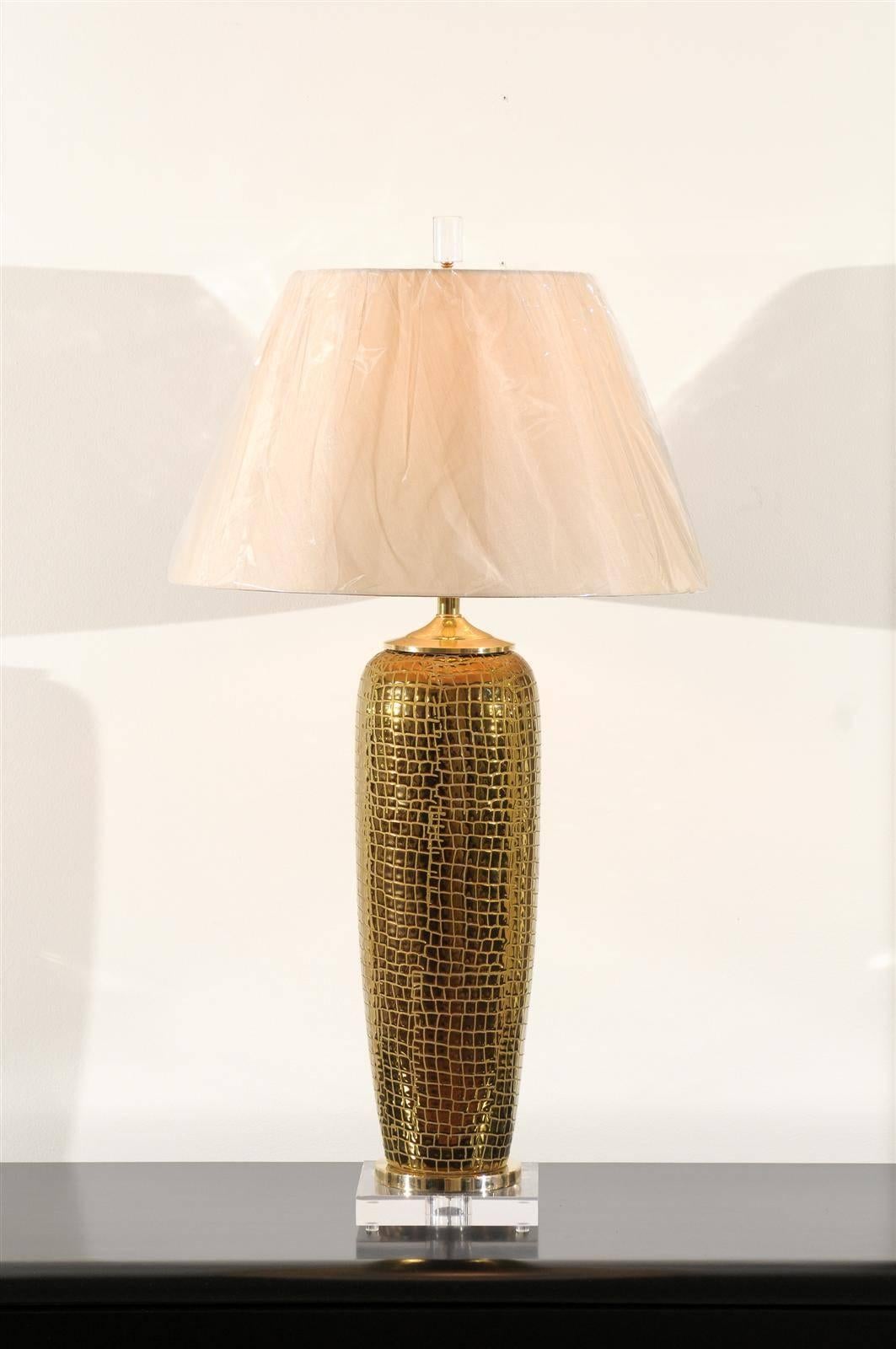 A sophisticated pair of large-scale custom-made lamps. Ceramic vessels in gold and embossed with a crocodile skin pattern. Solid brass accents and mounted on a new thick Lucite museum base. Beautiful color, sheen and texture. Exquisite jewelry!