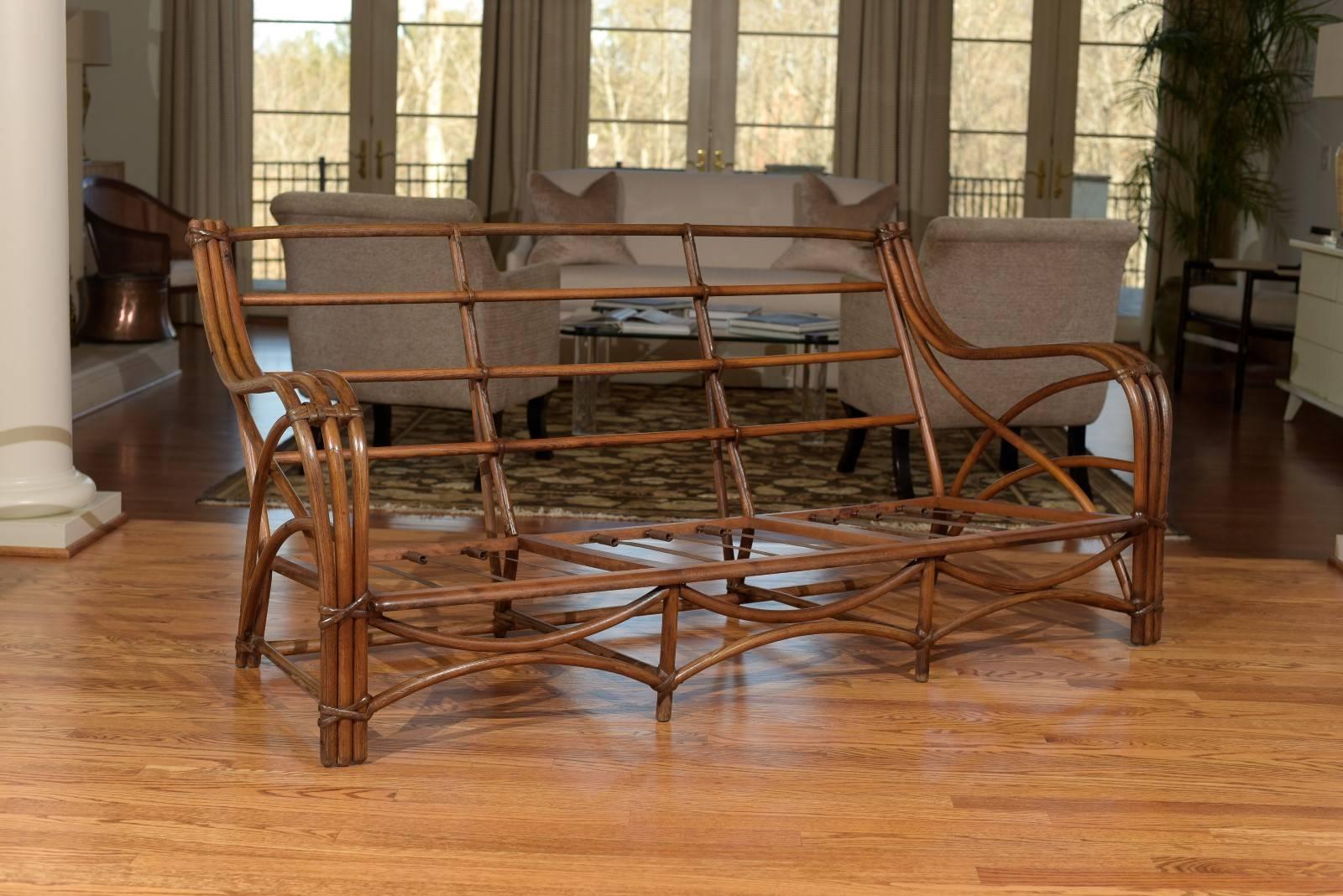 A beautiful and unusual sofa, circa 1950. Designed to give the appearance of rattan, the frame is actually made from bent oak. Sofa bindings and detail are in rattan. Stout and exceptionally crafted. The unmistakable look of old money. The matching