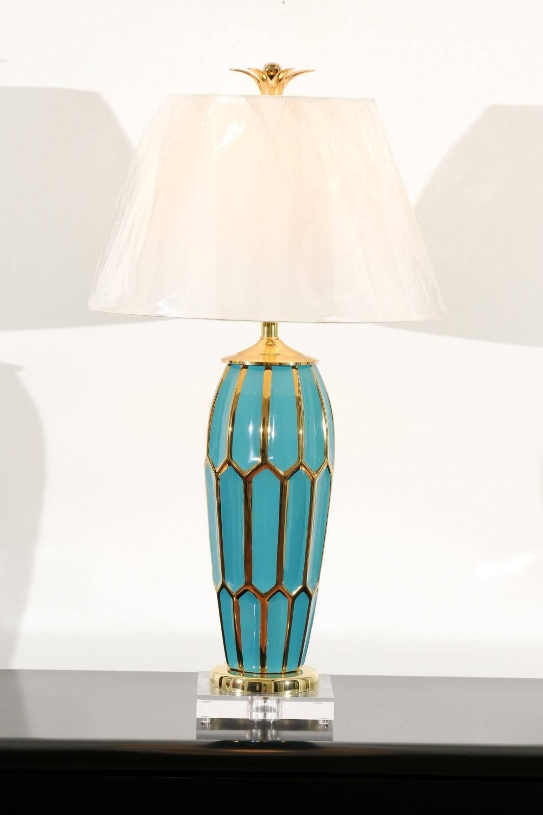 A stunning pair of ceramic vessels as custom-made lamps. Beautiful turquoise form with geometric motifs highlighted in gold. Accents in Lucite and solid brass. Custom-made brass petal and ball finials send the pair over-the-top. Incredible