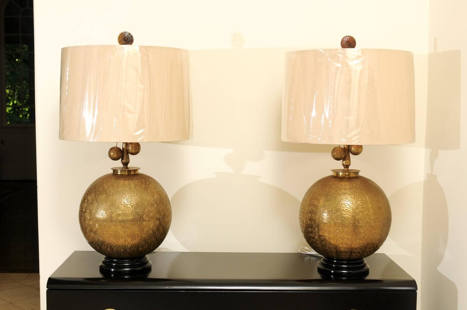 An exquisite pair of vintage brass sphere lamps, circa 1960. Hand-forged and etched brass form with fabulous scale and detail. Custom carved mahogany base finished in black lacquer. The pieces display slightly different embossed patterns. The