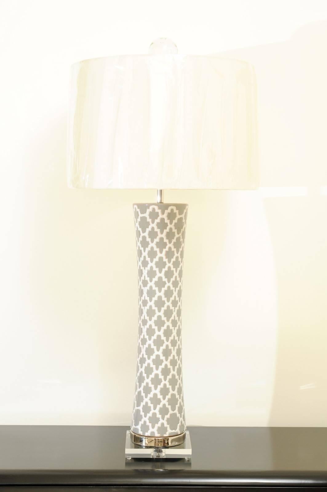 An exquisite pair of large-scale hand-painted ceramic vessels as custom-made lamps. Tall, elegant form with dramatic graphic motif; accents in polished nickel and Lucite. Custom-made clear blown glass finial ices the cake. Built using the finest