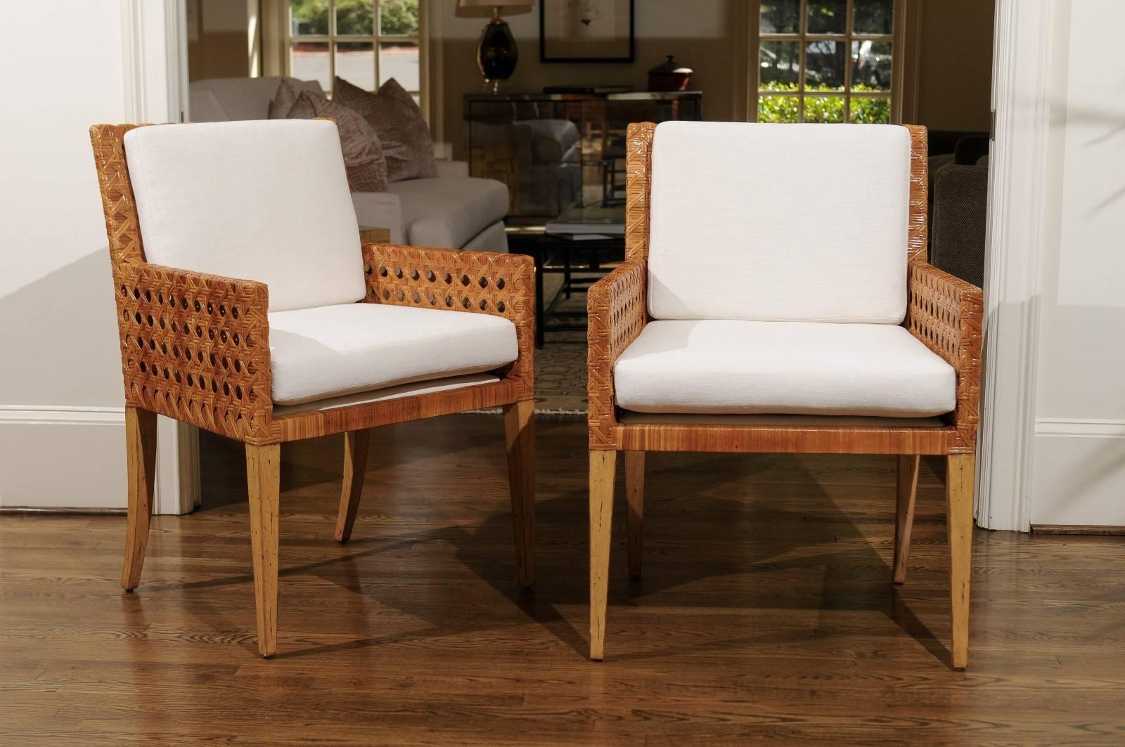 A exceptional pair large-scale arm or dining chairs, circa 1975. Stout hardwood frame construction painstakingly wrapped in double-sided cane. Fabulous quality and detail. Aged to absolute perfection. Exquisite jewelry! Excellent restored condition.