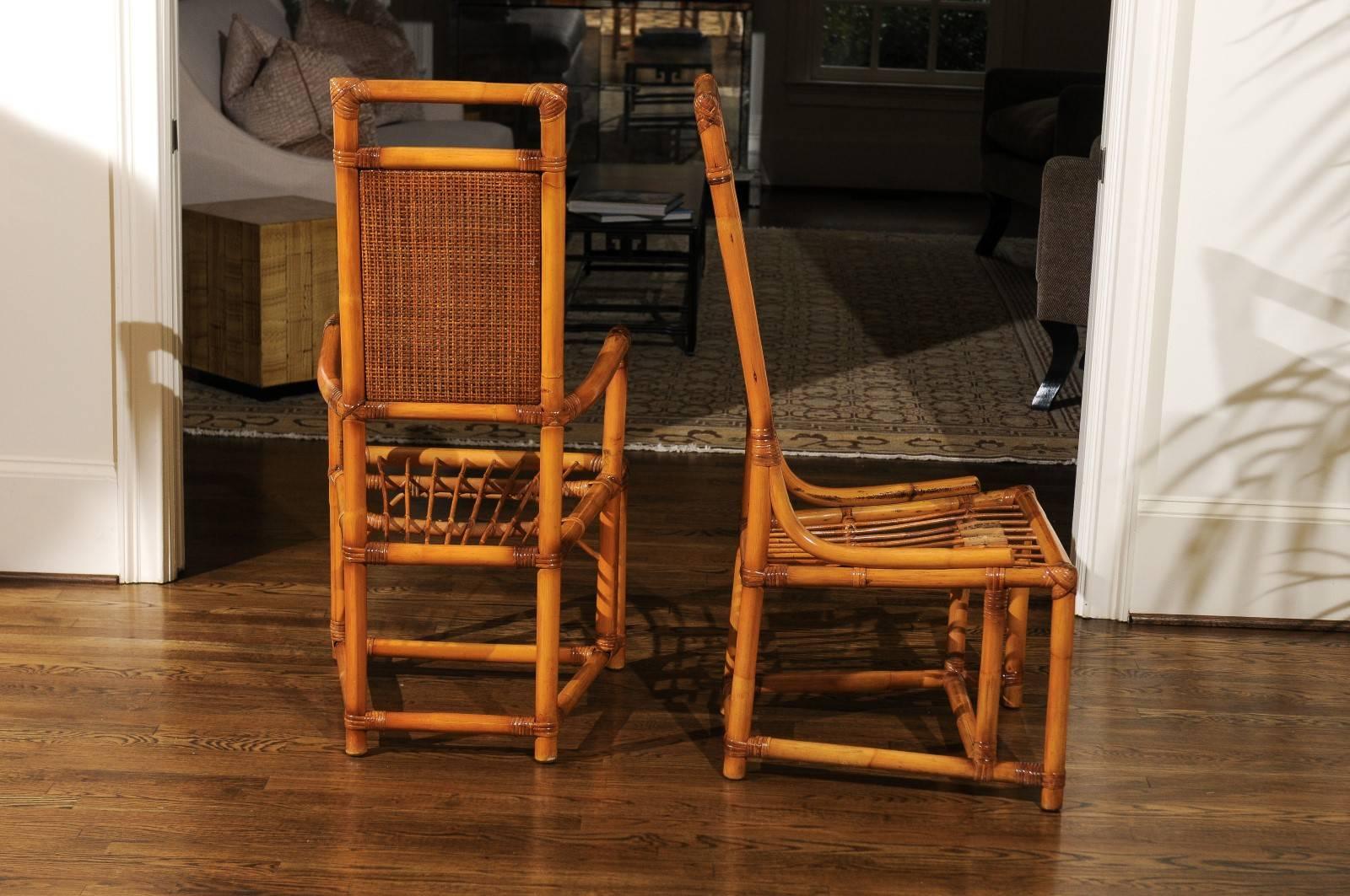 An exceptionally rare set of twelve (12) rattan and cane dining chairs, circa 1955. The set consists of one (1) host chair and eleven (11) side chairs. Stylish, beautifully conceived Throne style high-back design with a lovely double-sided cane