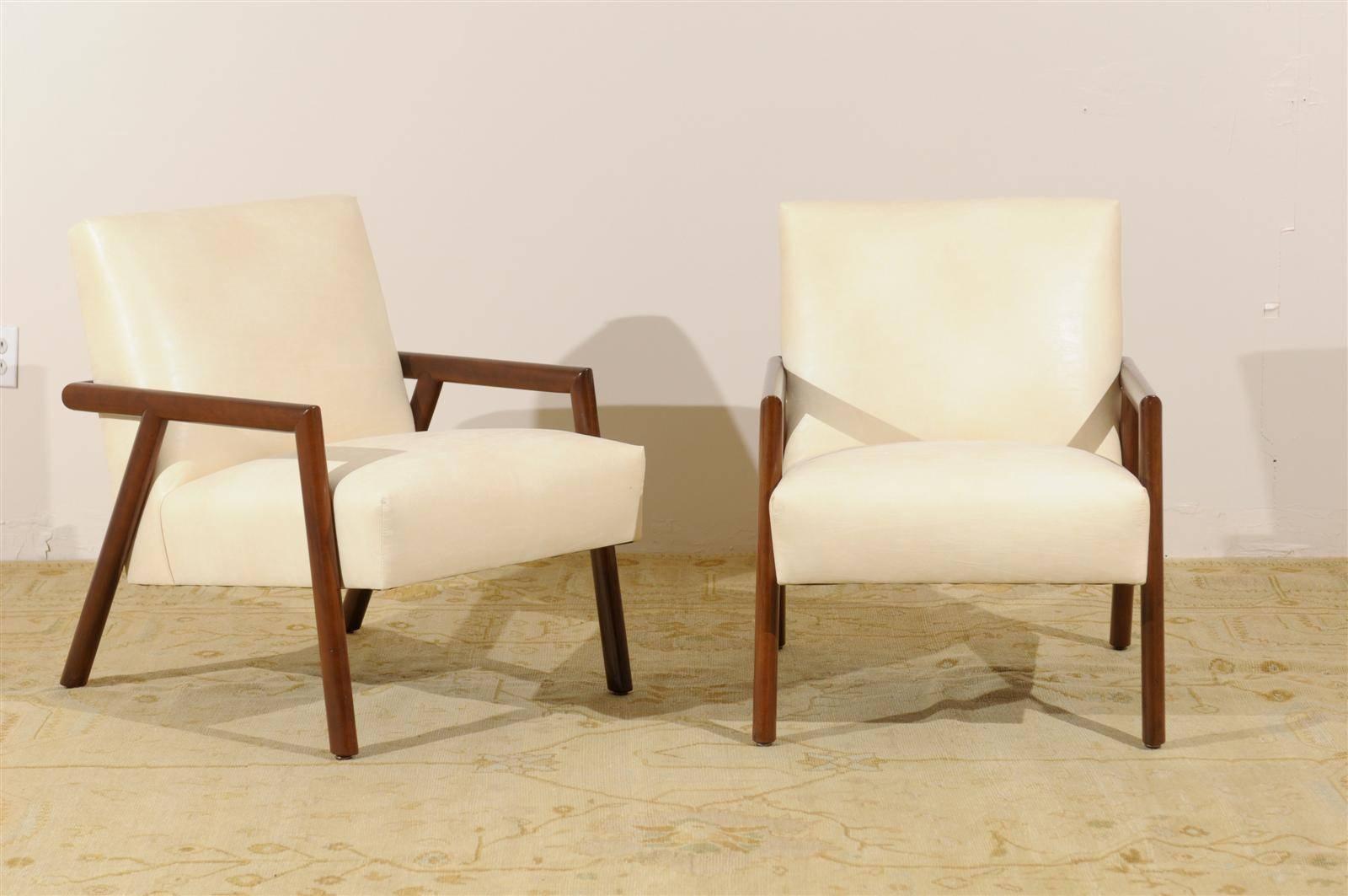 A beautiful pair of vintage modern Walnut lounge or club chairs.  New upholstery in a fine faux parchment fabric. Stout and very comfortable.  While the chairs are unmarked, they recall the Widdicomb lounge chair production of the 1950's.  Excellent