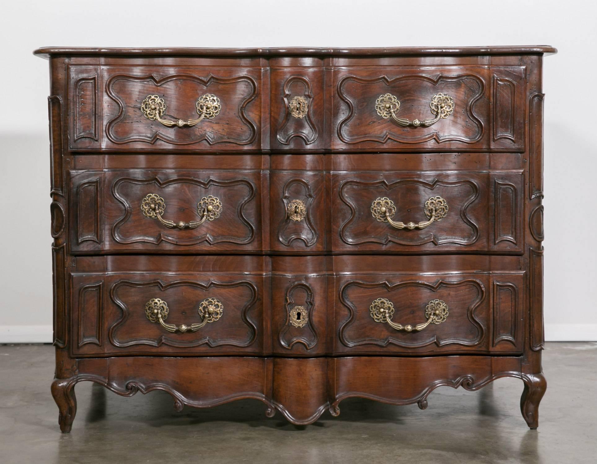A stunning and impressive 18th century period French Louis XV commode de chateau handcrafted in walnut by skilled artisans of the Lyon region. The front facade having an arbalete or cross-bow form with three drawers below a solid walnut top with