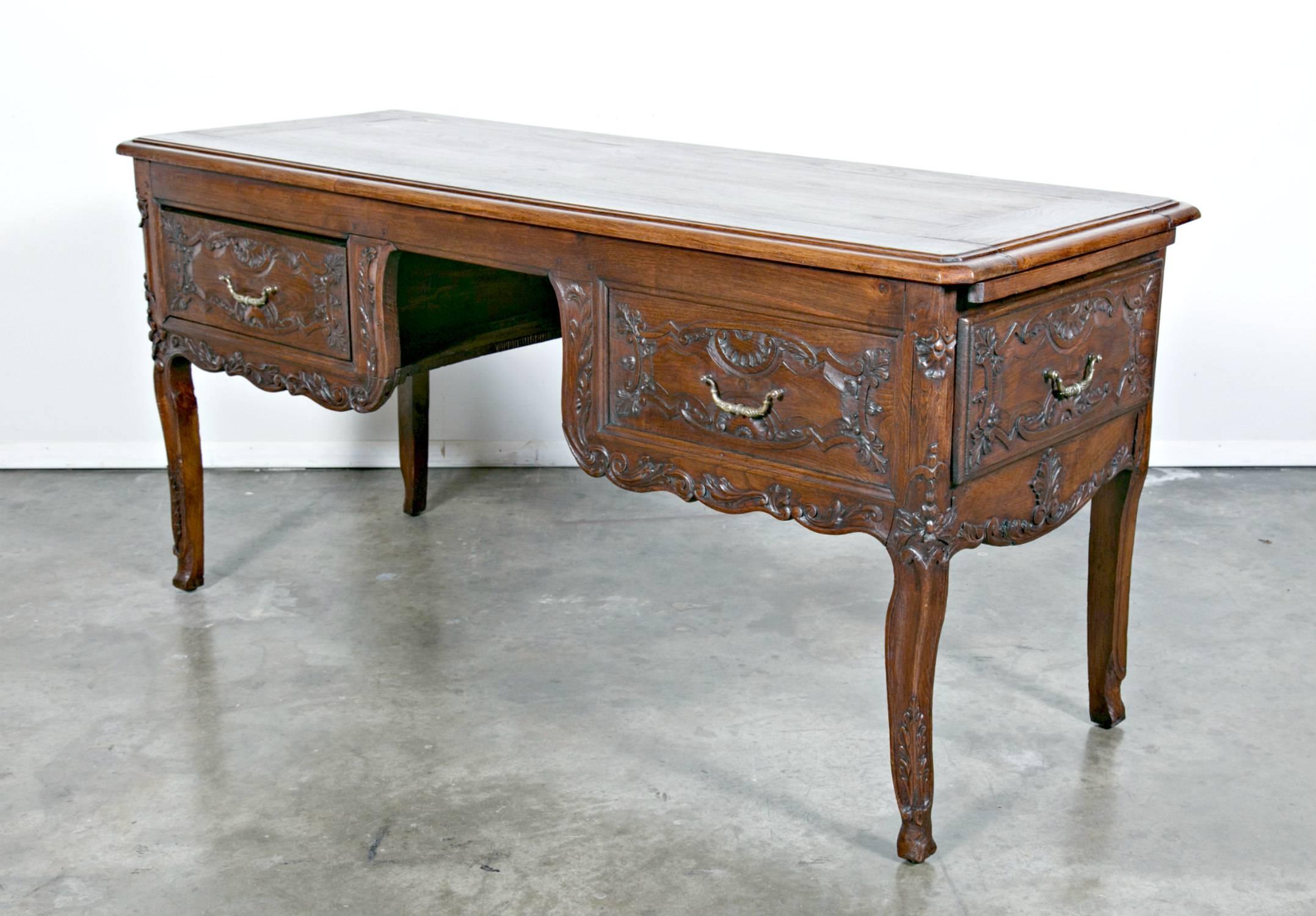 An early and very well crafted Louis XV style floating bureau plat, this fine writing desk is likely a product of the first quarter of the 19th century, perhaps a little earlier. Hand-carved with Regence-inspired artistry from solid French chestnut,