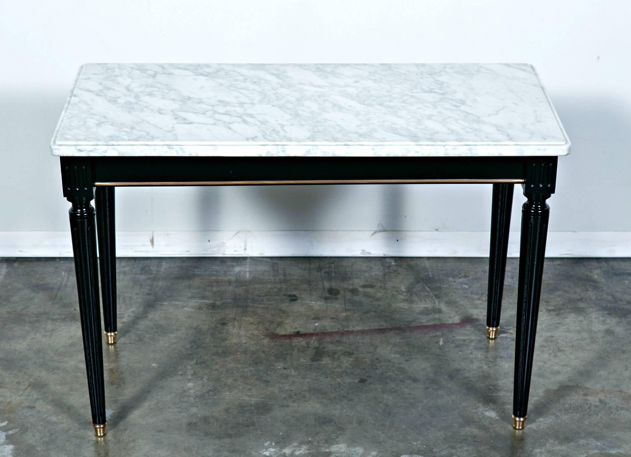 Classic French Louis XVI style coffee table in the manner of Maison Jansen, ebonized with a lustrous French polish, having brass trim and original Carrara marble top. Tapered, fluted legs ending in brass sabots. Mixes with other periods seamlessly.