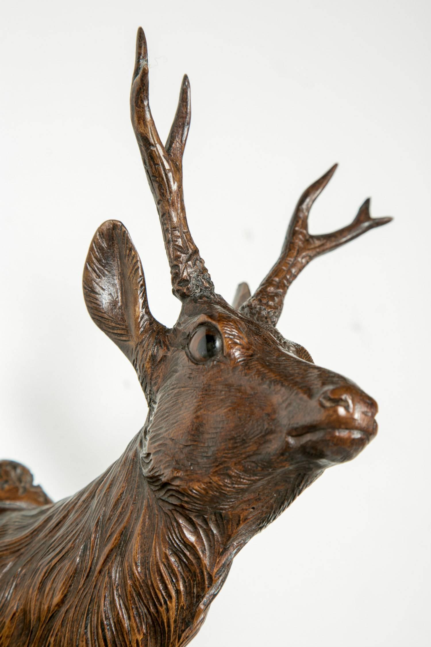 Intricately carved solid walnut Black Forest stag head gun rack having a beautifully carved stag's head at the top with glass eyes. The sides feature a total of six carved pegs as well as typical Black Forest leaf and vine carvings. This is a very