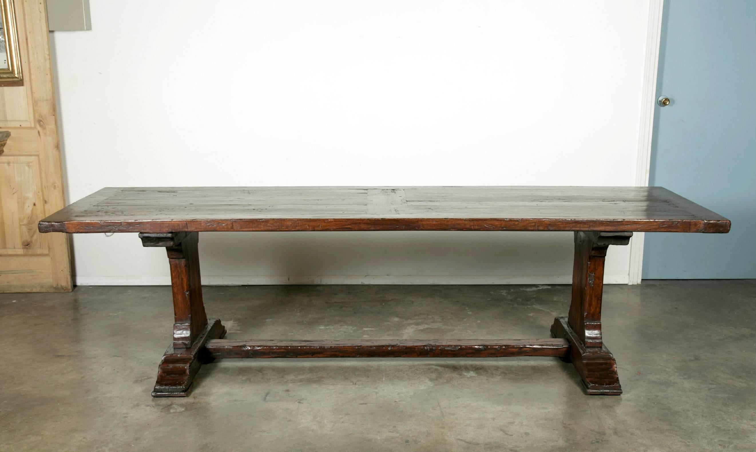 Antique trestle table handcrafted of solid walnut in the Lyon region during the 1850s, with room to seat four on each side and one on each end. The 2.25 inch thick rectangular inset board top is framed in chestnut and rests on trestle legs connected