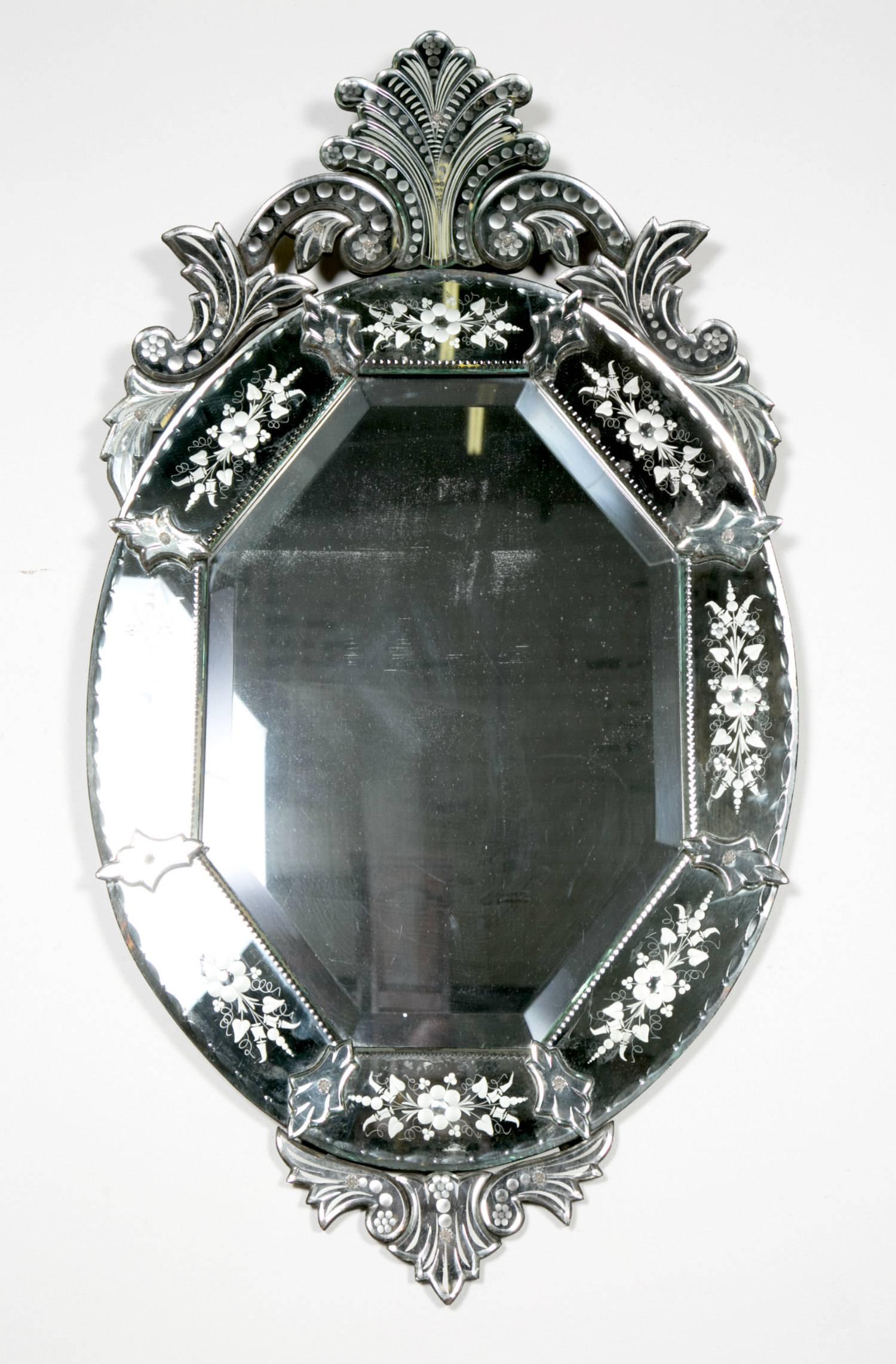A beautiful oval shaped Venetian mirror, circa early 1900s, with pierced glass pediment top, having original beveled mirror plates and engraved mirrored border sections secured with pins shaped as florets.

 
