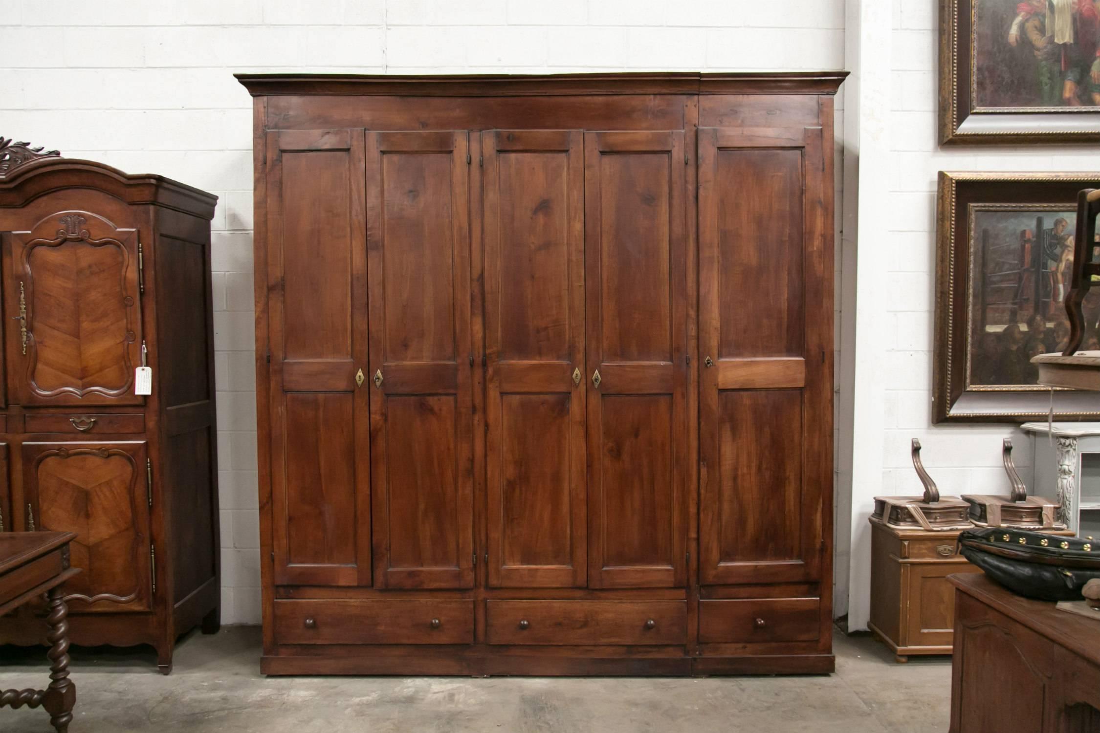 Monumental French Louis Philippe period placard or wardrobe handcrafted of cherrywood by skilled artisans of Mont Saint-Michel, an island commune in Normandy. custom-made for a nearby manor, having five paneled doors above three drawers, resting on