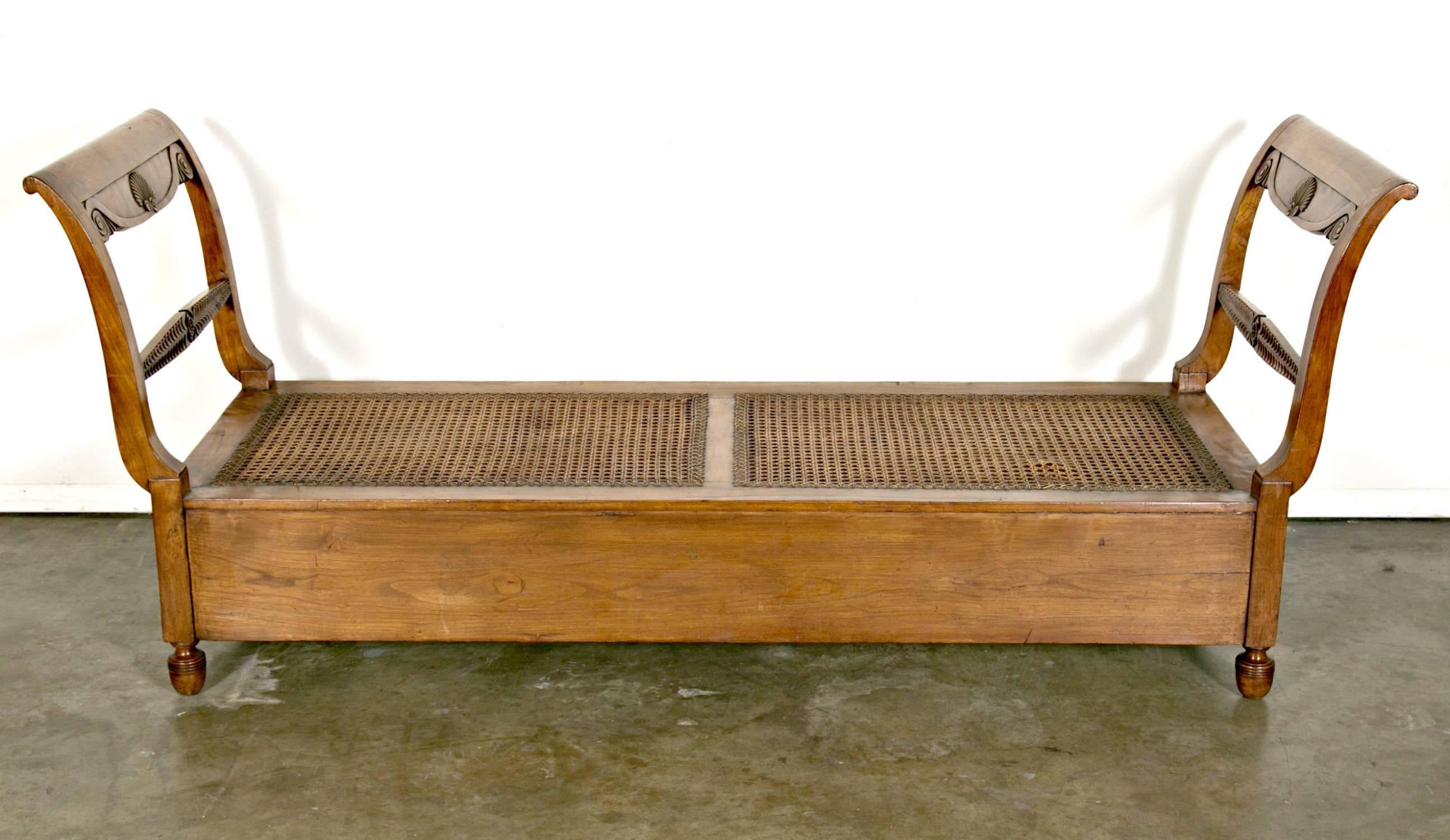 Lit de jour ancien en merisier de Provence, vers 1880. Doté d'une assise en rotin d'origine et d'une riche patine, ce charmant lit de jour aux courbes douces et aux sculptures typiquement provençales présente un design simple, mais élégant. Le lit