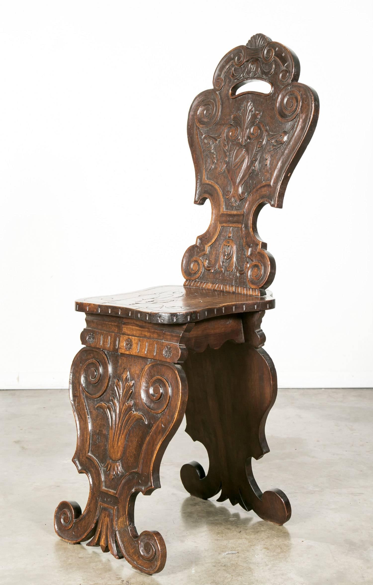 A wonderful 18th century Italian carved walnut Sgabello chair. The entire surface is covered with boldly carved decoration from top to bottom with the seat having an incised decorated surface. The tall back has sculptural and symbolic carvings with