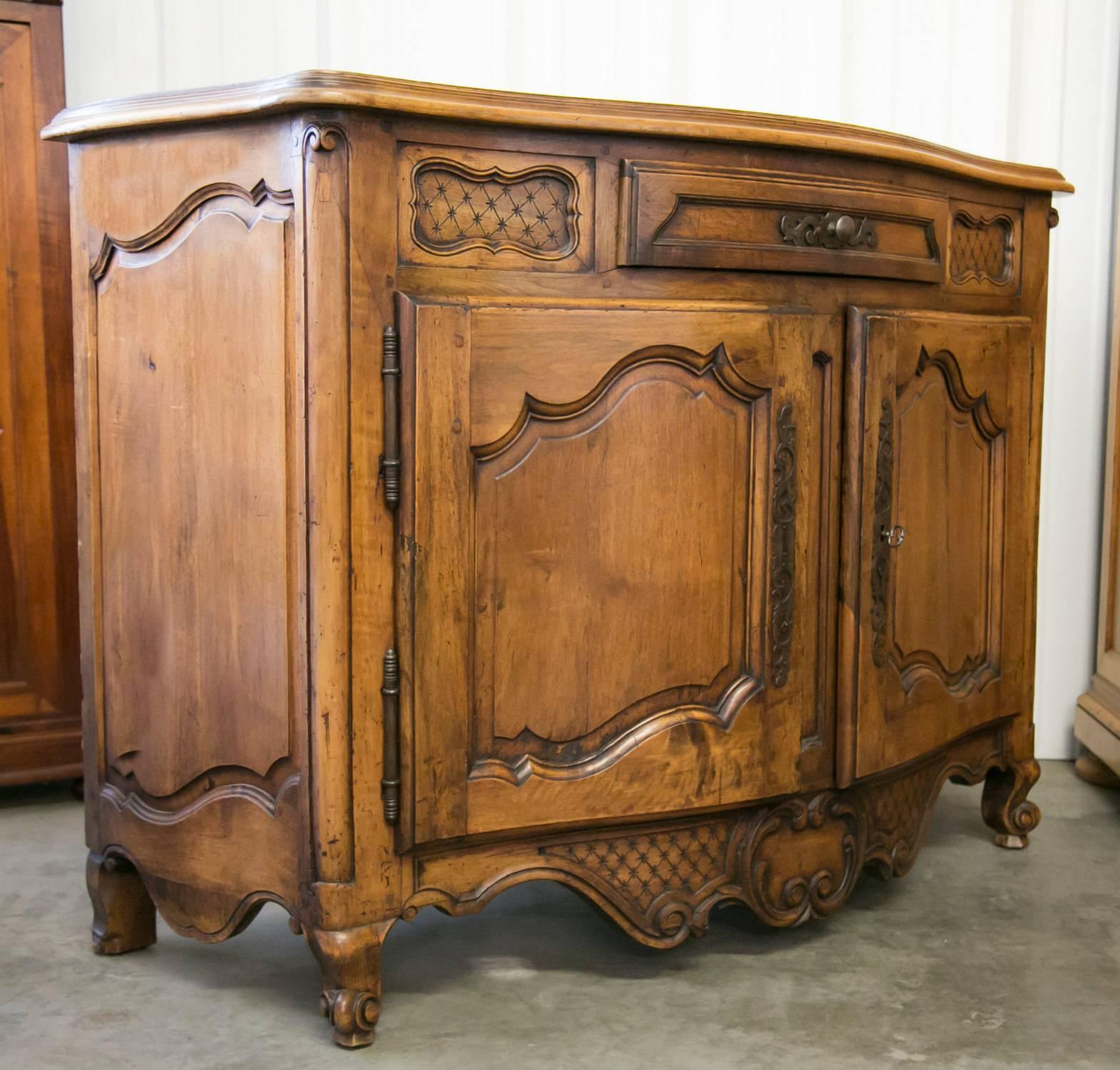 A fine 19th century Louis XV style Provençal buffet of solid walnut having a moulded serpentine top over a center drawer flanked by beautiful carved cross hatch panels all above two moulded paneled doors with carved C-scrolls ending in volutes. The