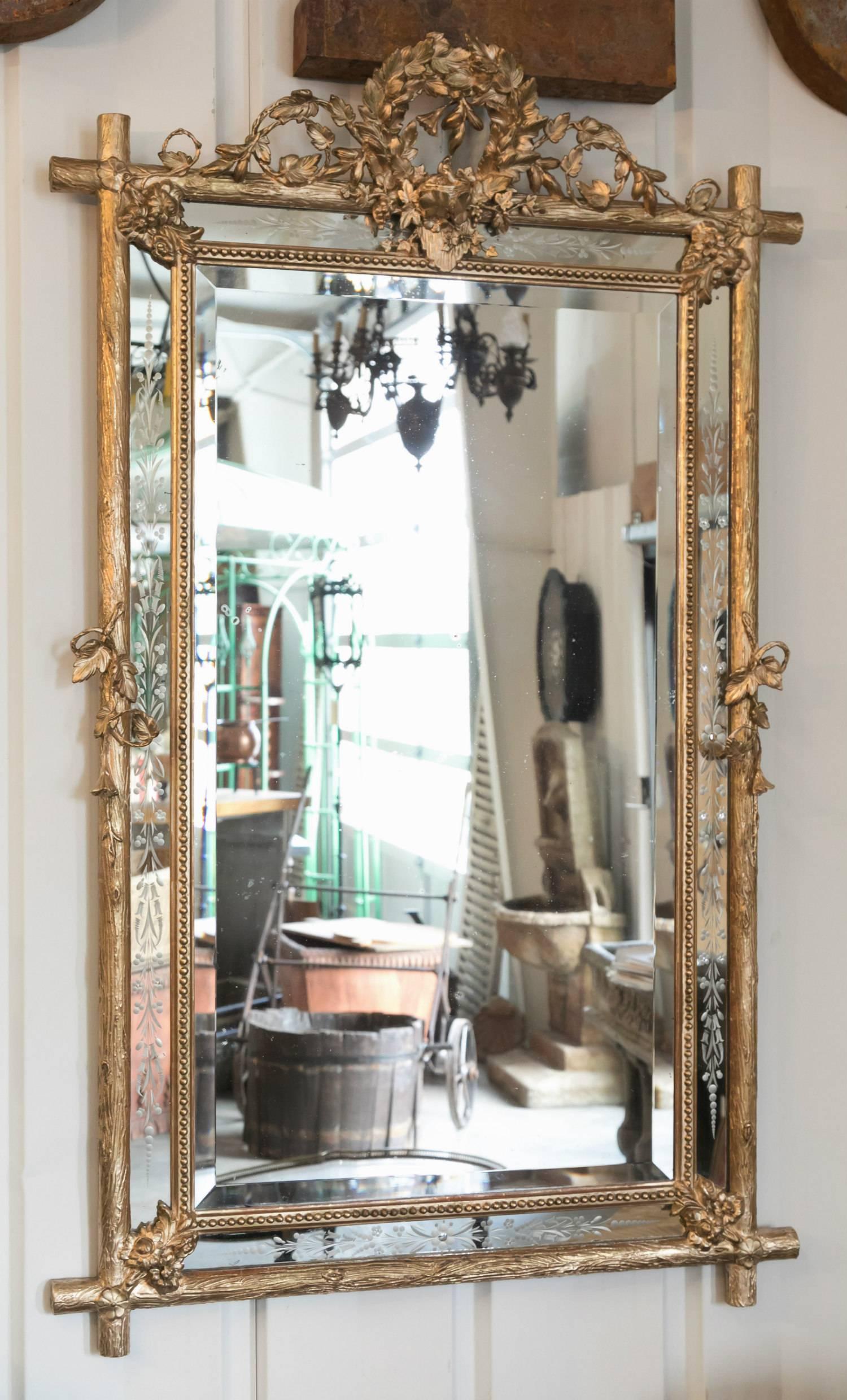 Stunning French giltwood faux bois framed mirror with beaded centre frame, having a grape vine, olive wreath, and rose crest with heavy gilt carvings of flowers and leaves. Typical of Provençal work, the giltwood frame is simple in form with a