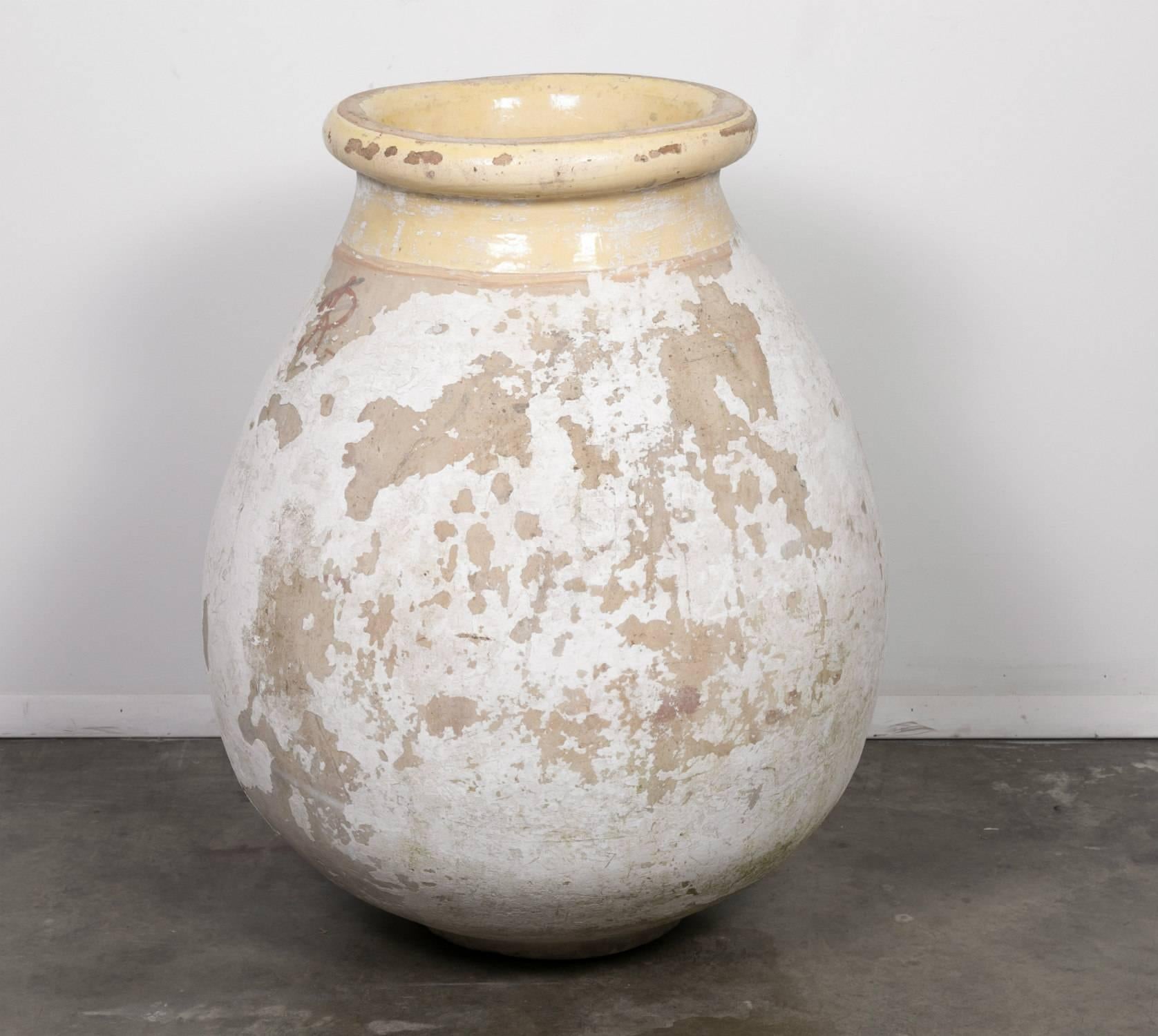 This large 19th century French biot is a classic French olive jar with a lovely aged patina and glazed pale yellow neck and chateau mark. The small village of Biot, located in Provence, has been producing the iconic terracotta pottery since the 16th