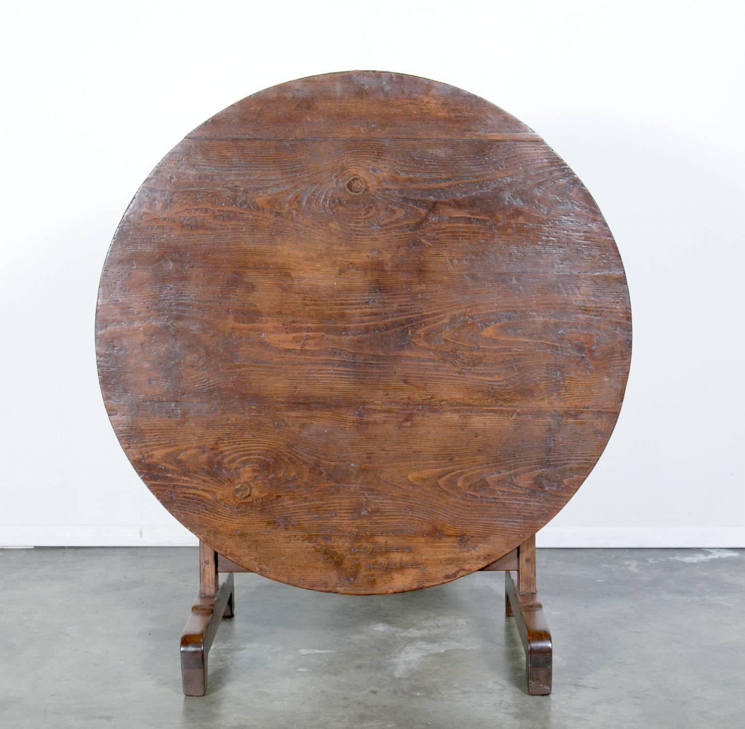 This French wine table with typical tilt-top dates back to the 1850s and features visible wood grain patterning on the pine table top. The base is chestnut. Table has a rich color and nice patina. These tables were originally used in the vineyards
