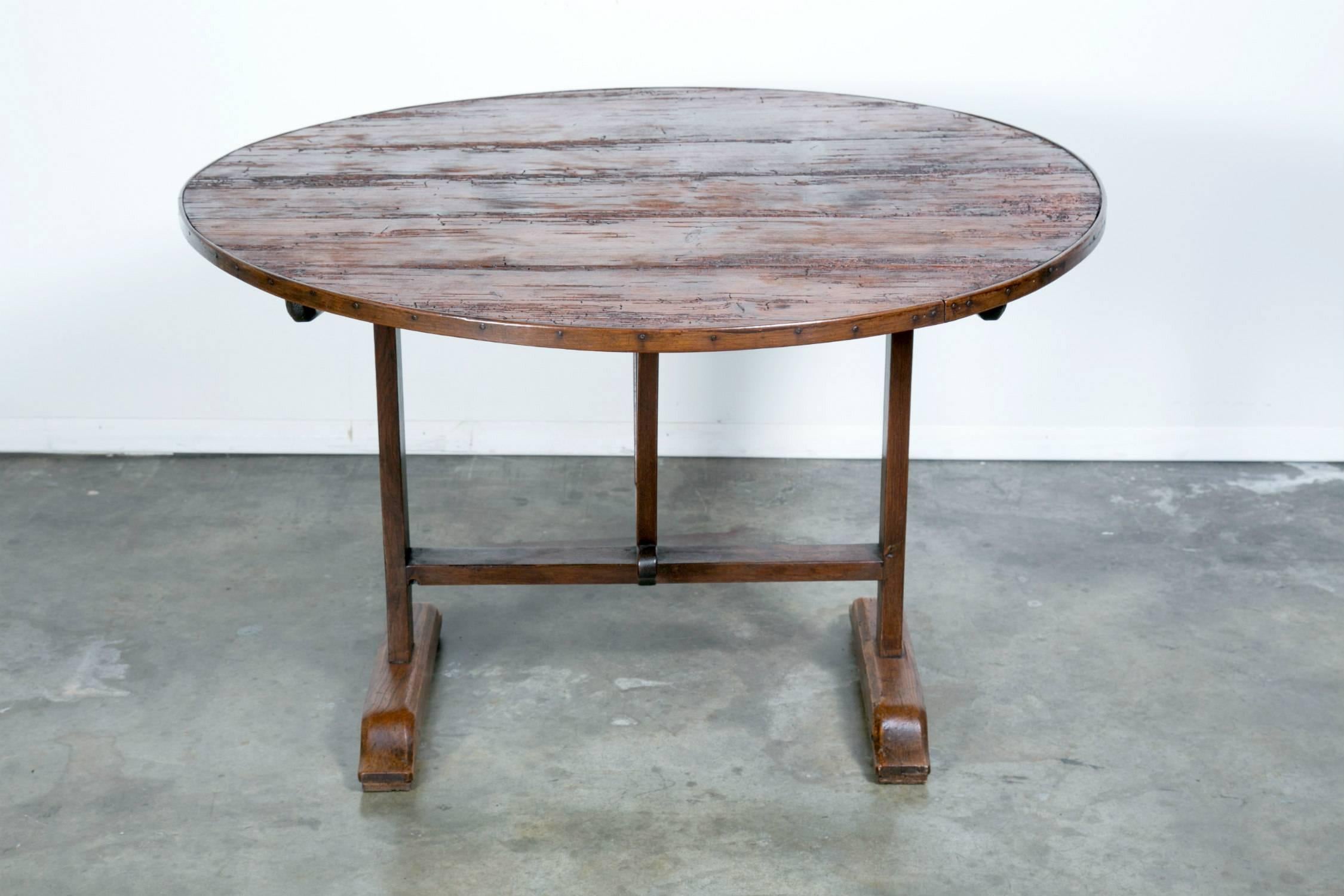 Rustic French wine table with typical tilt-top that allows the table to stand against the wall when not in use. Dating back to the mid-1800s, this superbly crafted vendange table features a round, plank top in pine and a chestnut base with wooden