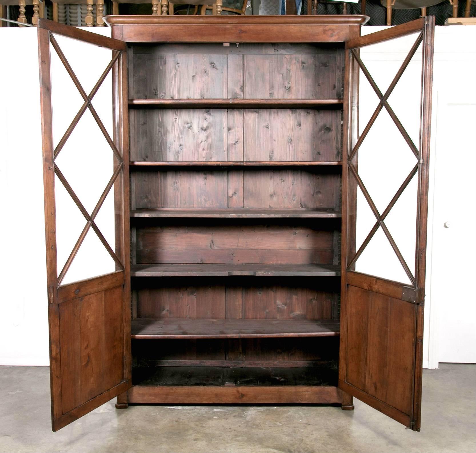 Elegant 19th century French period Louis Philippe bibliotheque (bookcase) handcrafted of solid cherry by talented artisans near Mont Saint-Michel, an island commune in Normandy, having a molded cornice above a pair of three-quarter glass paneled