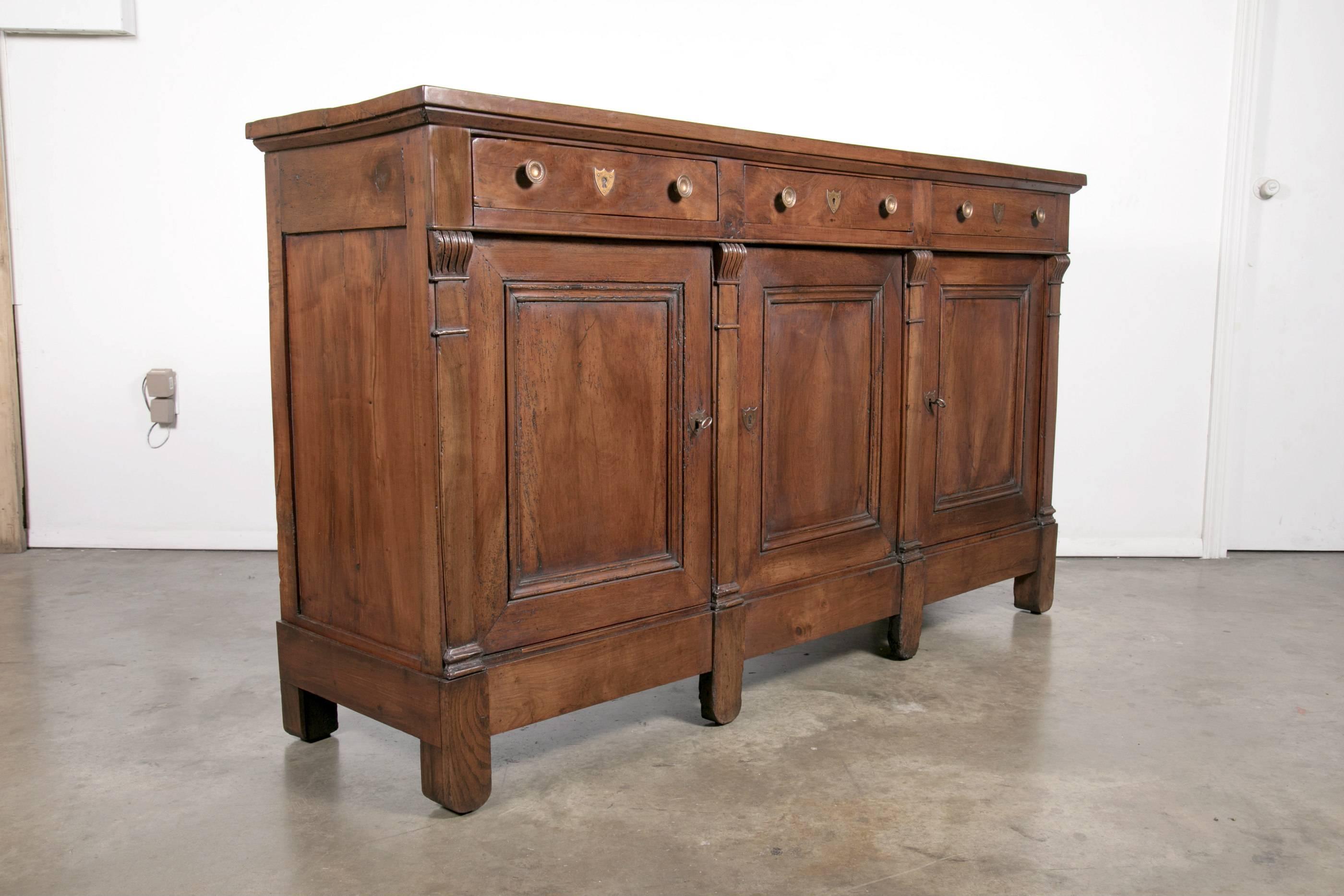 Antique French solid walnut Directoire period enfilade buffet handcrafted by talented artisans from Lyon. Paneled top above three drawers and three paneled doors divided by pilaster columns with original bronze hardware. Spacious interior storage.