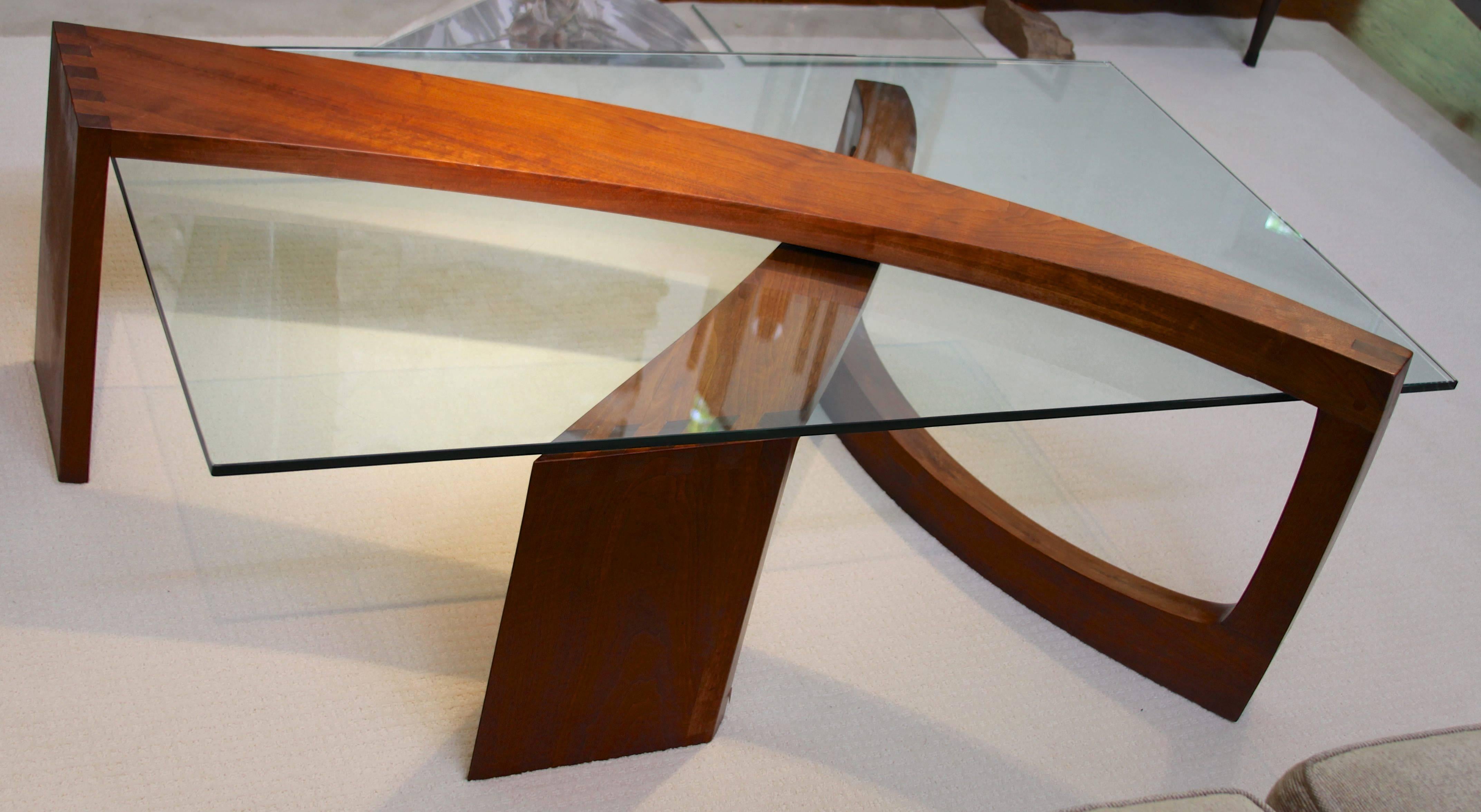 Walnut dovetailed structure supporting a rectangular glass plate.
