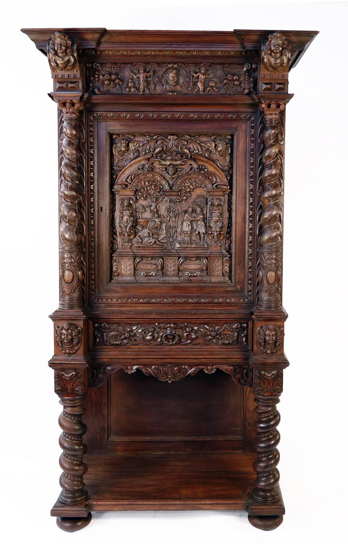 Heavily carved, the shaped top over a frieze carved in relief with a portrait medallion and putti holding brooms and fruiting vines, over a hinged cabinet door carved with scenes from the life of Jacob, with Solomonic columns flanking, above a
