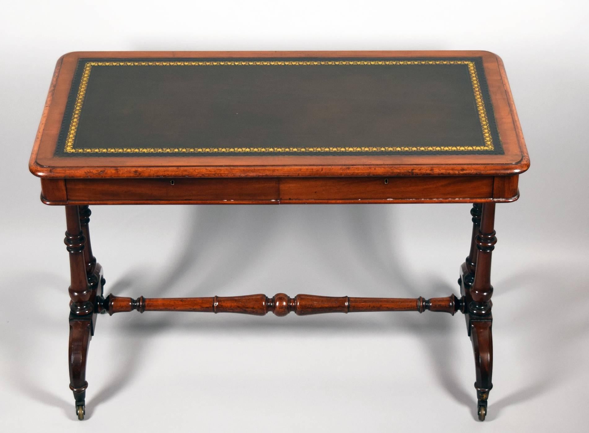 Elegant carved and turned trestle writing table with two drawers supported by two turned slender pillars on each side over an arched two footed base with brass casters.

Provenance: Roundwood Manor, Hunting Valley, Ohio.
