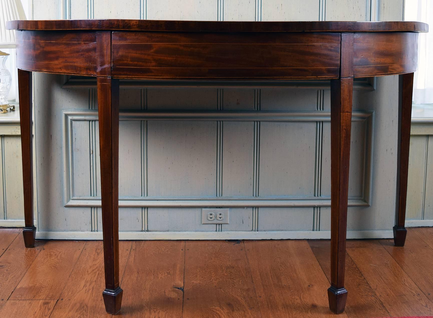 The D-shaped top with a conforming single frieze drawer line inlaid, raised on squared tapering legs, line inlaid, ending in spade feet

Provenance: Roundwood Manor, Hunting Valley, Ohio.