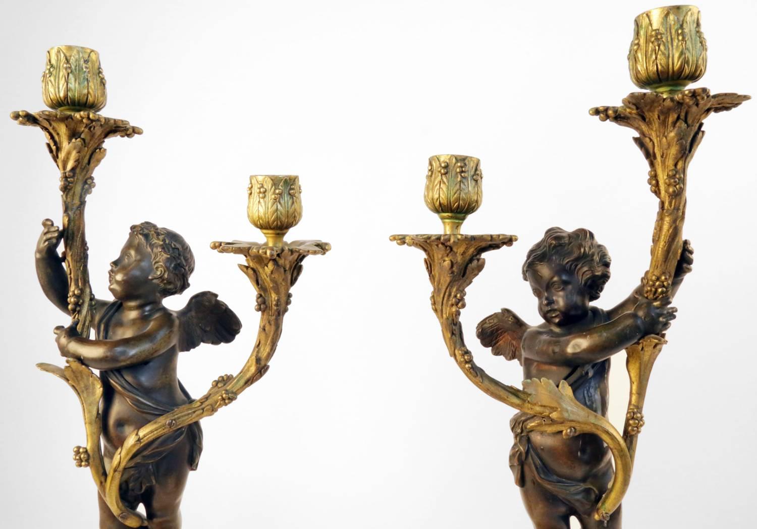 Cast in the form of a pair of winged cherubs supporting foliate branches issuing bobeches and candle sconces, raised on rectangular yellow marble and bronze bases.