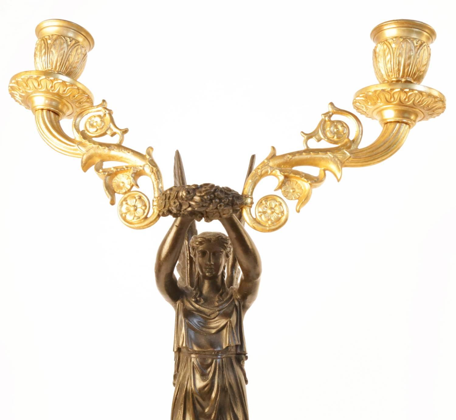 Each cast in the form of a winged female goddess balanced on a bronze sphere, holding aloft a wreath issuing a pair of voluted scrolls and a pair of candle sconces, all on squared bronze bases with wreath form decoration.