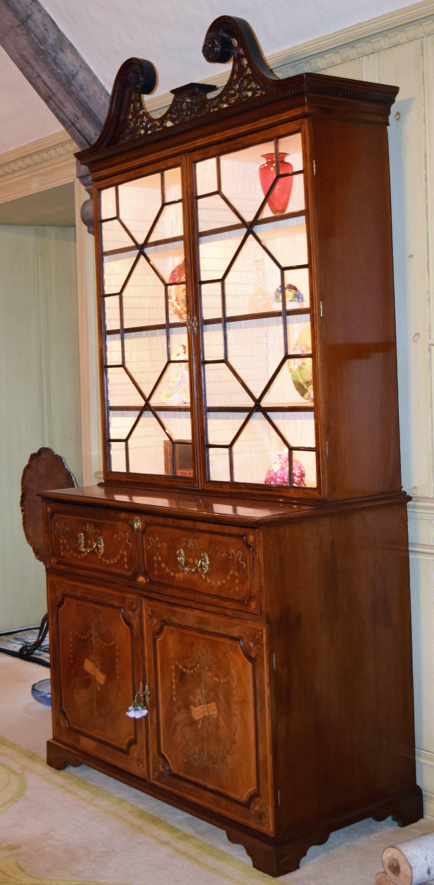 Mahogany and satinwood inlaid 13 lite secretary bookcase with reticulated broken arch pediment over a fitted leather top desk above two inlaid doors on bracket feet.

Inlaid with floral swags with a musical motif, circa 1770.

Provenance: