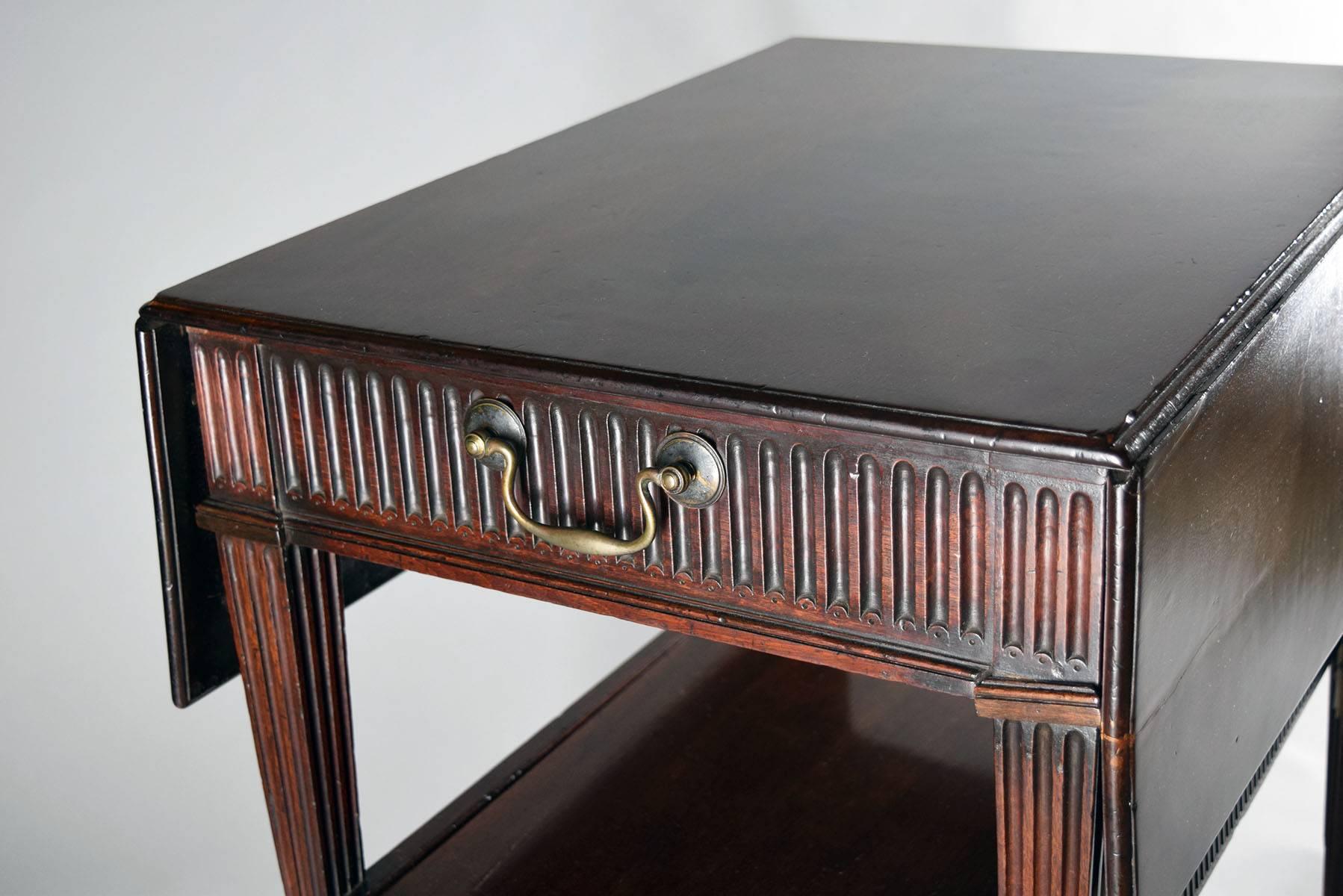 Rectangular top with two drop leaves over a fluted single drawer with retractable felt lined writing surface, raised on squared tapering fluted legs joined by a stretcher shelf, the legs ending in block feet and casters.

Provenance: Roundwood