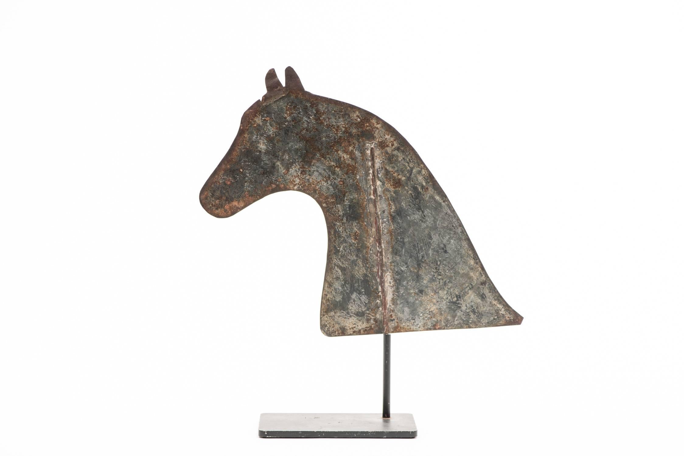 Horse weathervane.

Region: Northeast, 

circa late 19th century.

Materials: Tin, iron post, solder.

Dimensions: H 11” x W 12”.

Condition: Overall good. Weathered surface, oxidation, minor cracks to horse’s ears. No restoration. 
