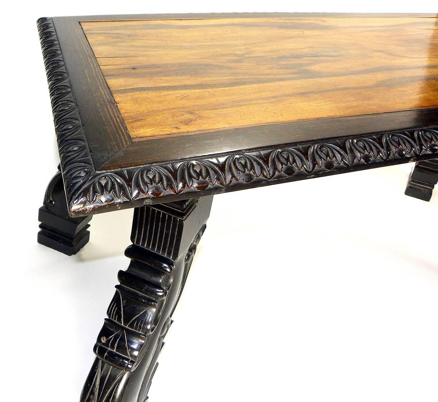 A rectangular topped tabled with leaf tip carving around the edge, the top resting on striking carved and out-swept legs of solid ebony. Probably Ceylon. 