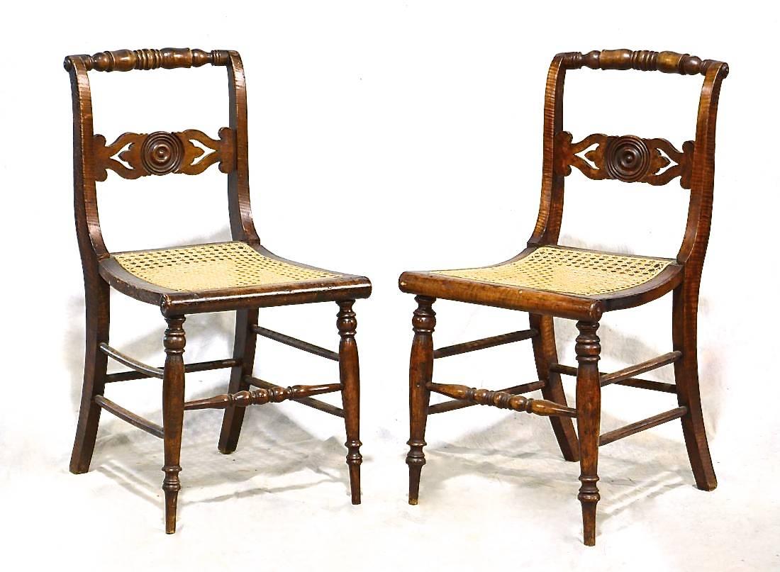 A set of eight American Federal period dining chairs, ca. 1815-1820, with a distinctive bull’e eye carved rondel within the shaped backsplats. Each seat rests on slim turned legs in the front, backswept sabre legs in the back. The chairs have a nice