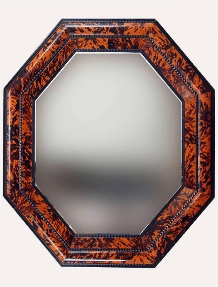 A Flemish style deeply moulded mirror of impressive size, with concentric bands of narrow ripple carved ebonized wood and wider faux painted tortoiseshell mouldings. Beveled mirror plate with some attractive speckling and anomalies. Can be oriented