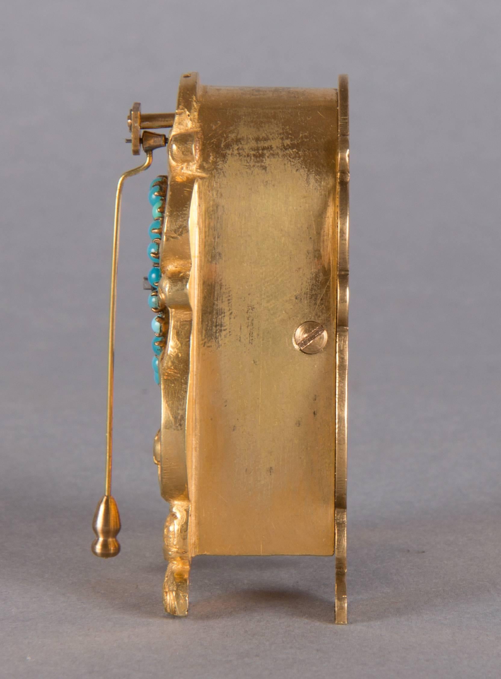 Measures: Height 6.5 cm 
Fire gilt brass case, turquoises, enamel dial, hook escapement.