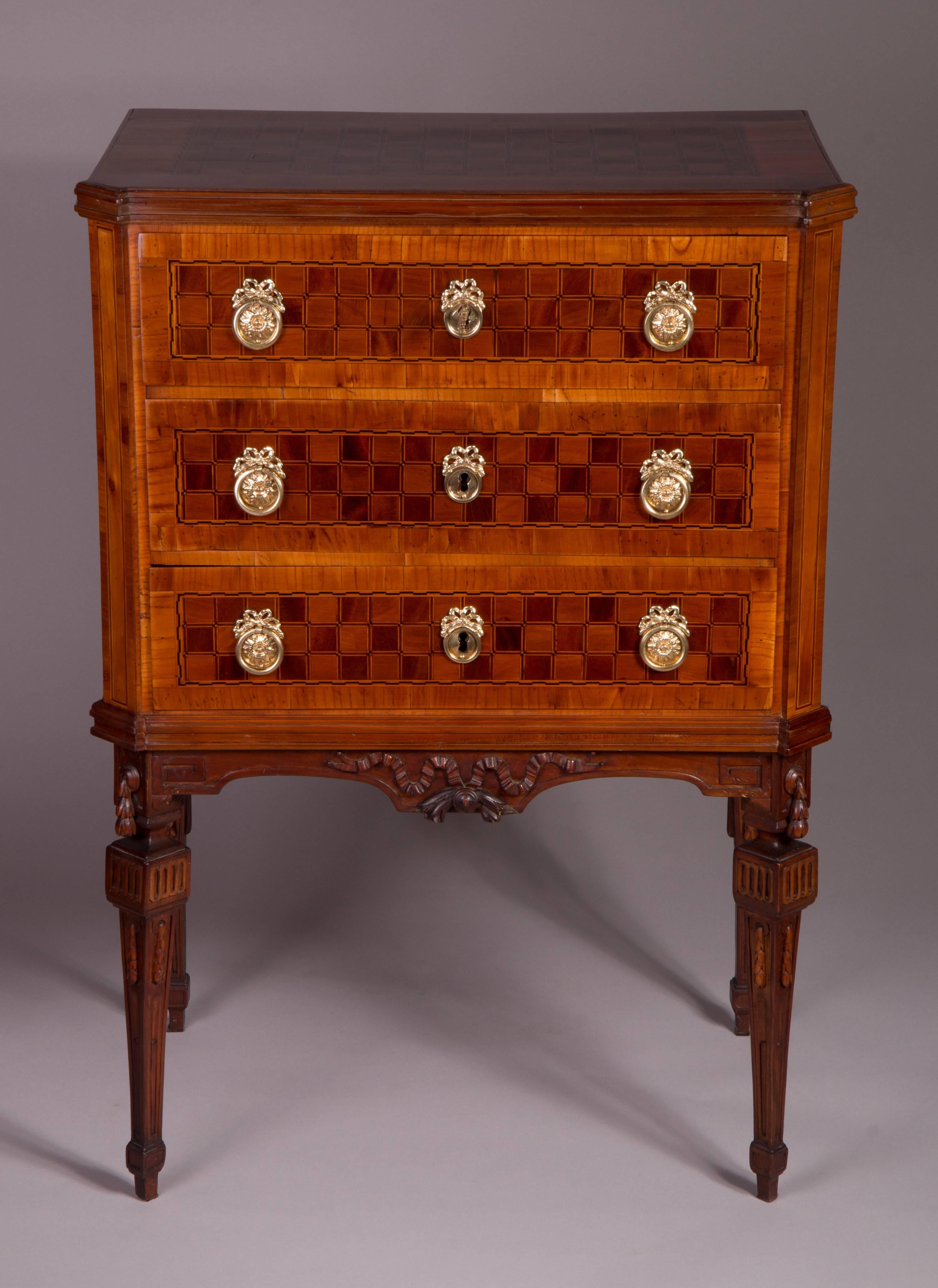 Cherry veneered, marquetry with walnut and maple, cocked pilaster strips, three drawers, carved tapered legs.