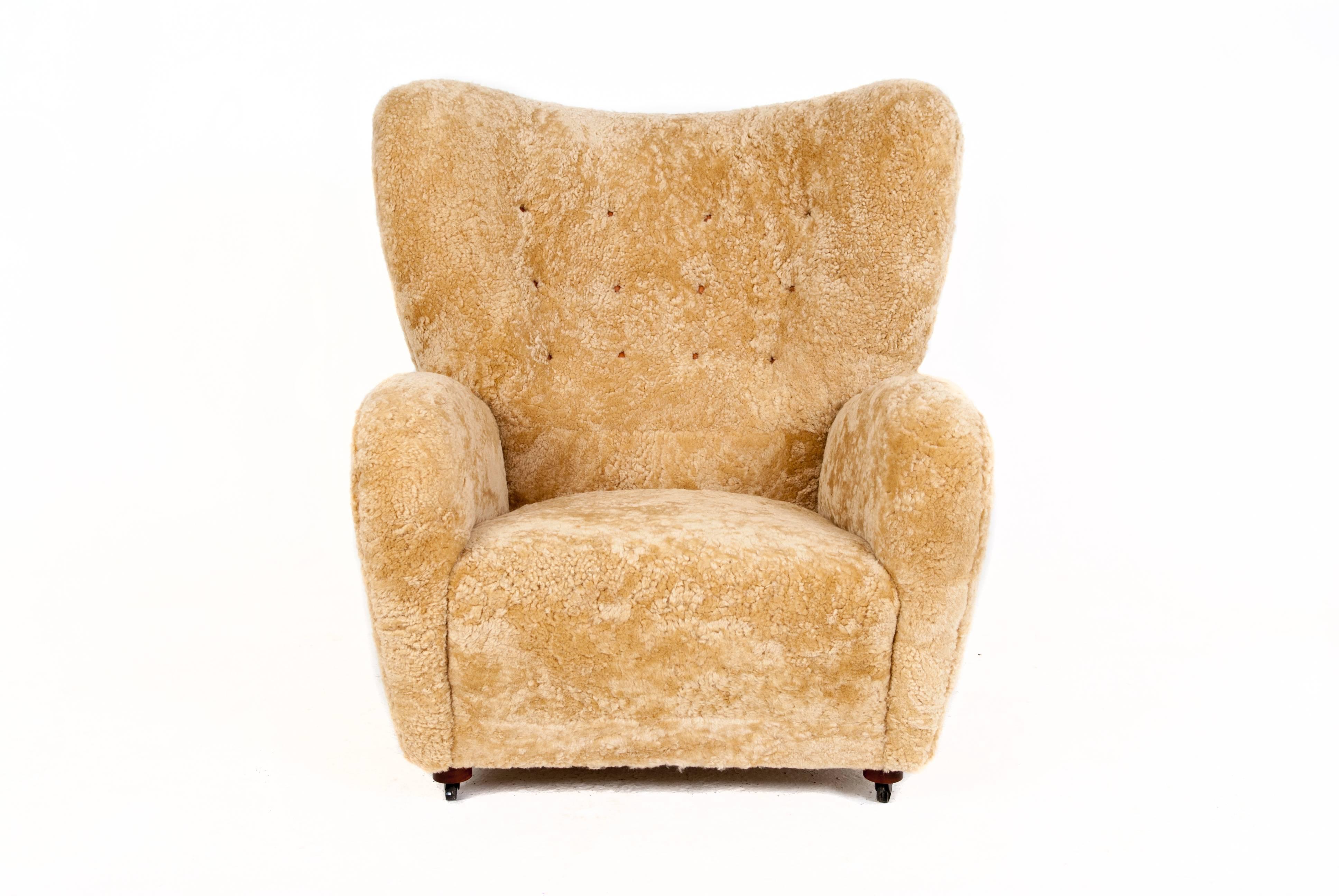 Flemming Lassen attributed. 

Easy chair upholstered with honey colored sheepskin, partly fitted with leather buttons. Wheels as front legs.

 