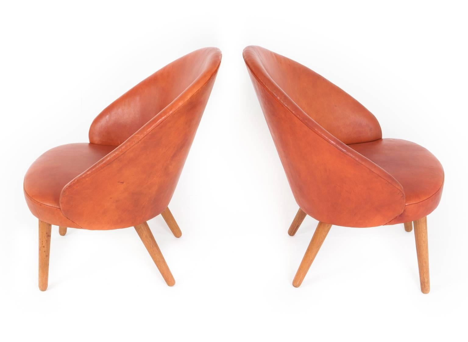 Ejvind A. Johansson. 

A pair of easy chairs with curved back and oak legs, seat and back with patinated red/brown leather
Model 301

 Designed 1958
 Manufactured by Godtfred H. Petersen.
 