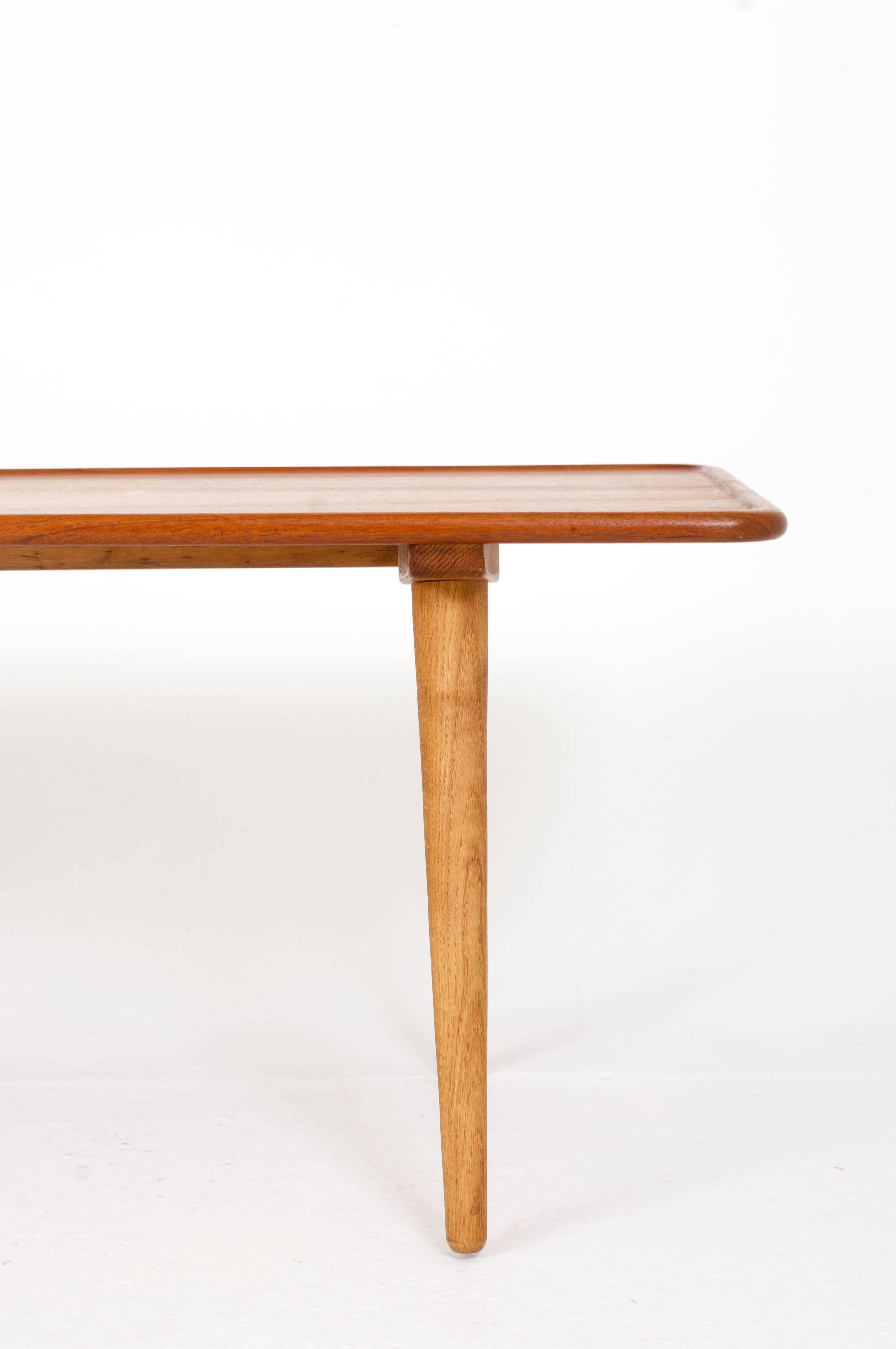 Hans J. Wegner

Rectangular solid teak and oak coffee table with angled legs, top with raised edge. 

Manufactured by Andreas Tuck, Odense. 

Designed ca 1955