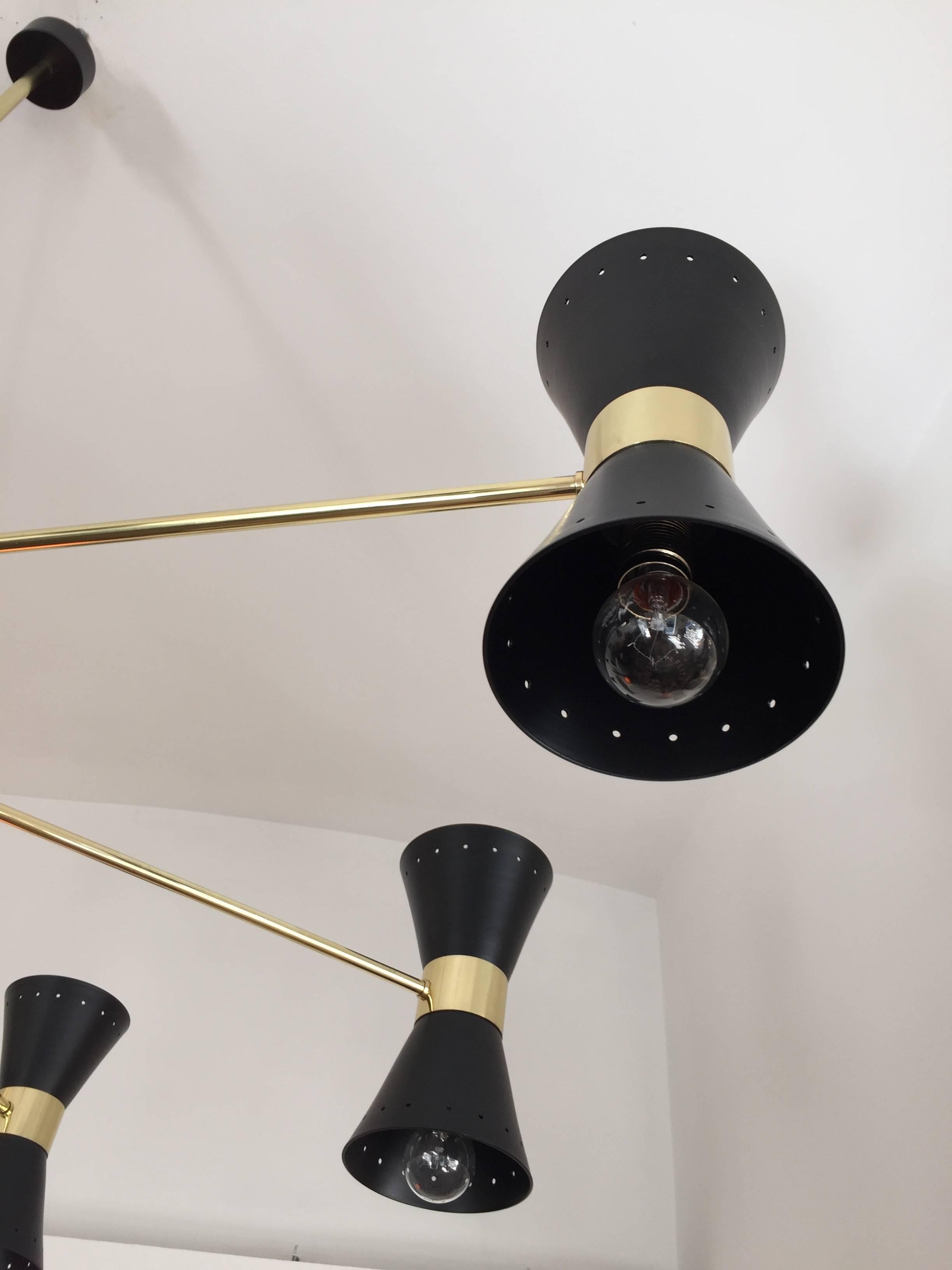 Wonderful and rare brass and black lacquered Italian manufactured Sputnik chandelier. Fully restored in very high quality with new electric. 
This Mid-Century Modern chandelier has eight arms that hold black lacquered diabolo shaped double cones.